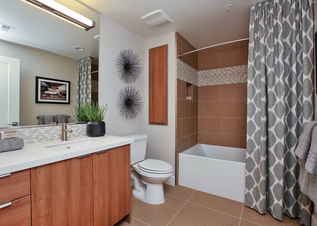 Interior view of AMLI Uptown Orange apartment bathroom with quartz countertop and large soaking tub with tile surround