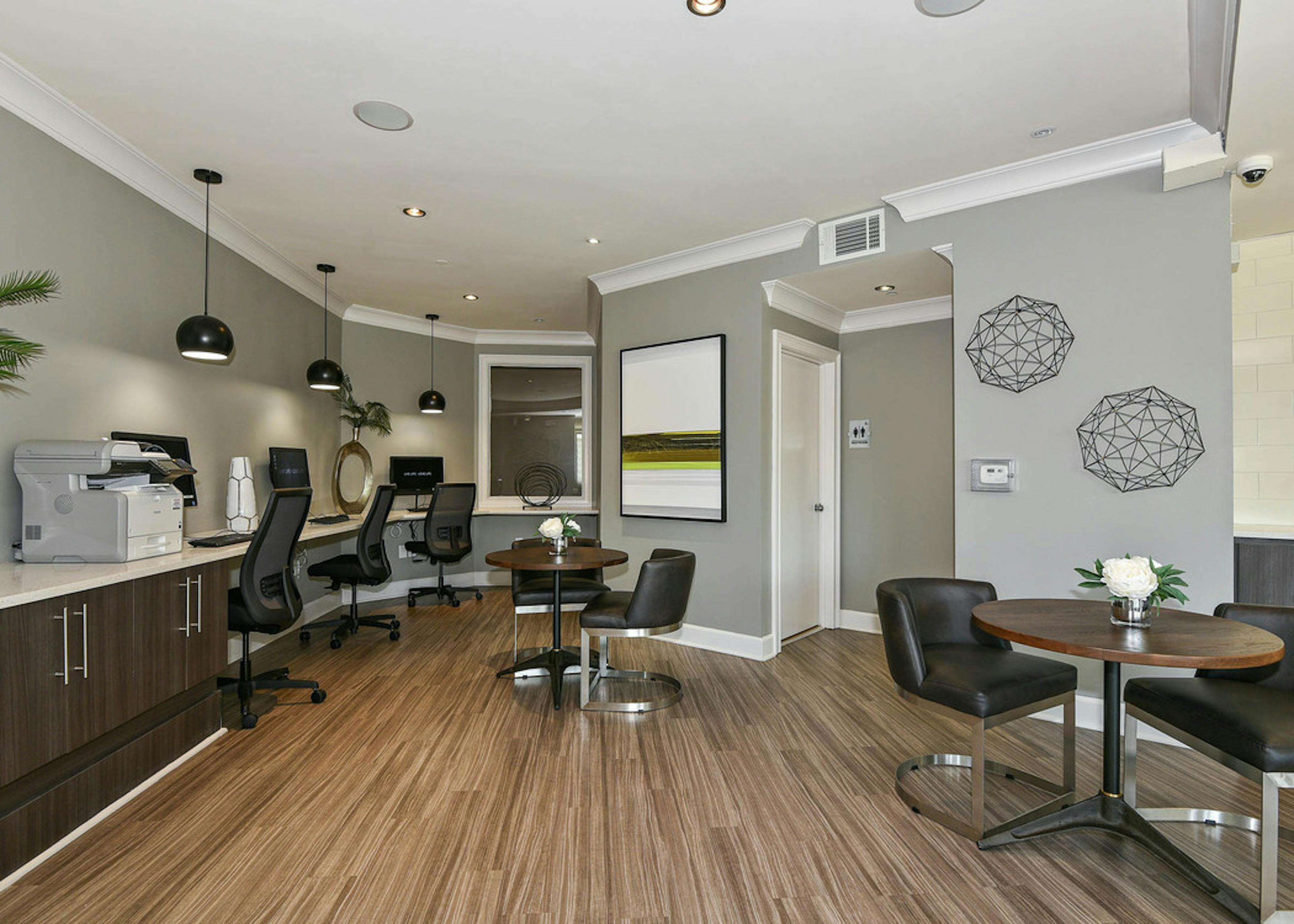 Interior view of AMLI Lindbergh apartment business center with three computer desktops and a printer with tables and chairs