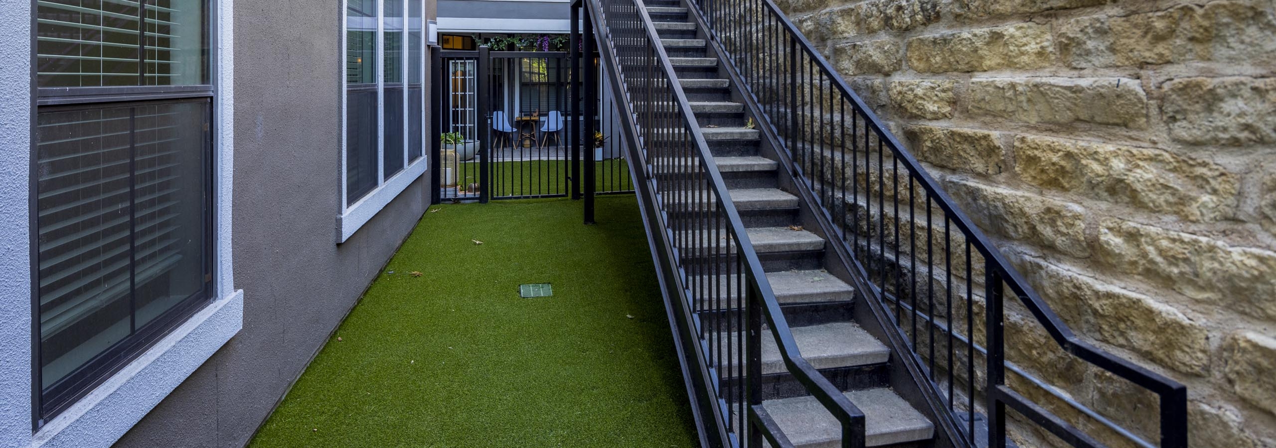 Oversized apartment yard at AMLI Eastside apartments with green turf and a black staircase leading to the main street