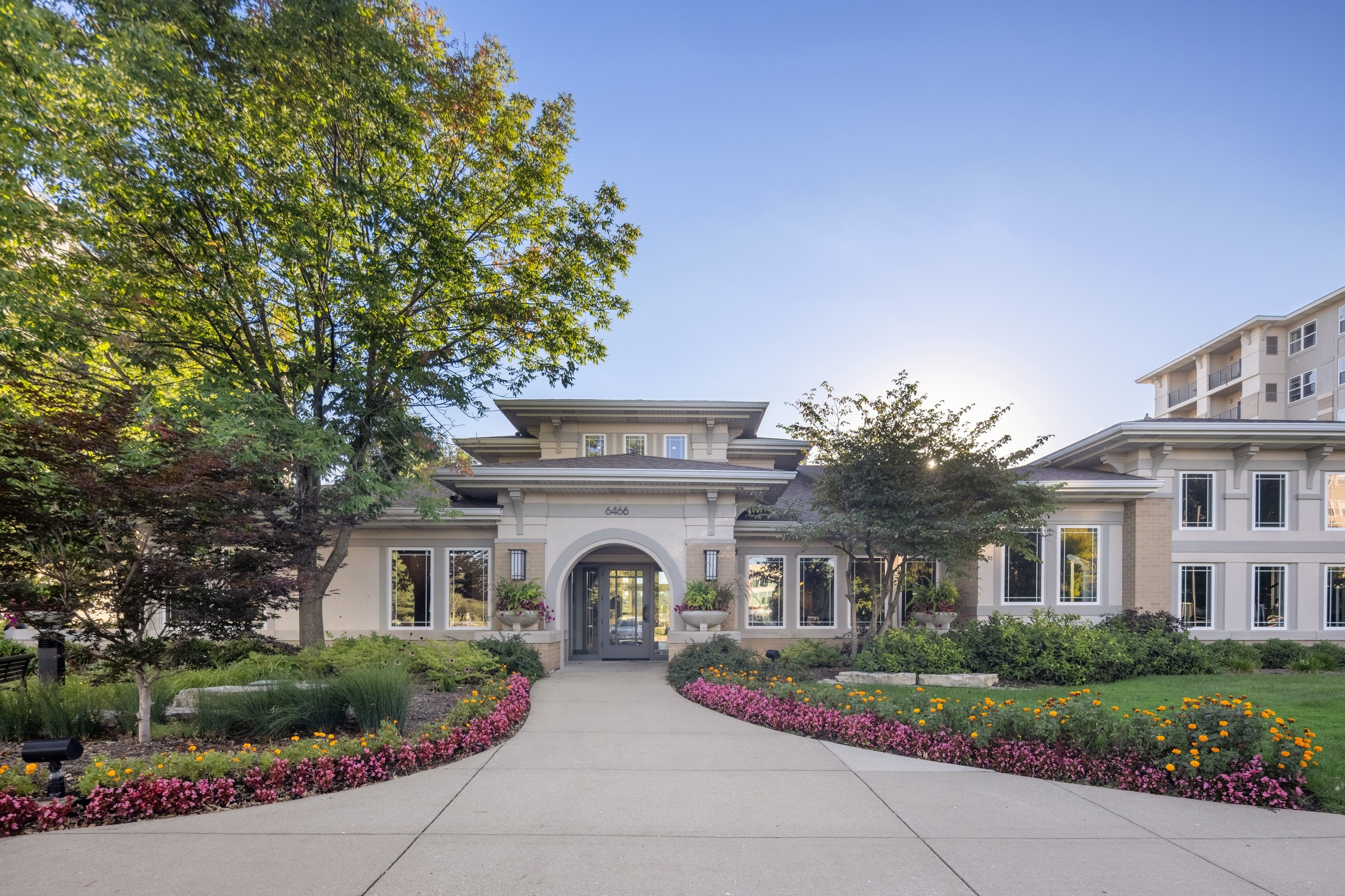 Exterior view of the AMLI at Seven Bridges apartment community clubhouse building surrounded by colorful flowers