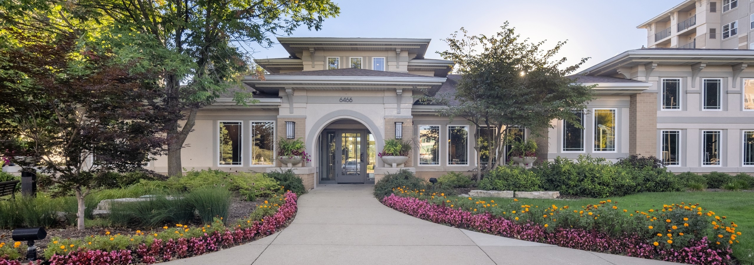Exterior view of the AMLI at Seven Bridges apartment community clubhouse building surrounded by colorful flowers