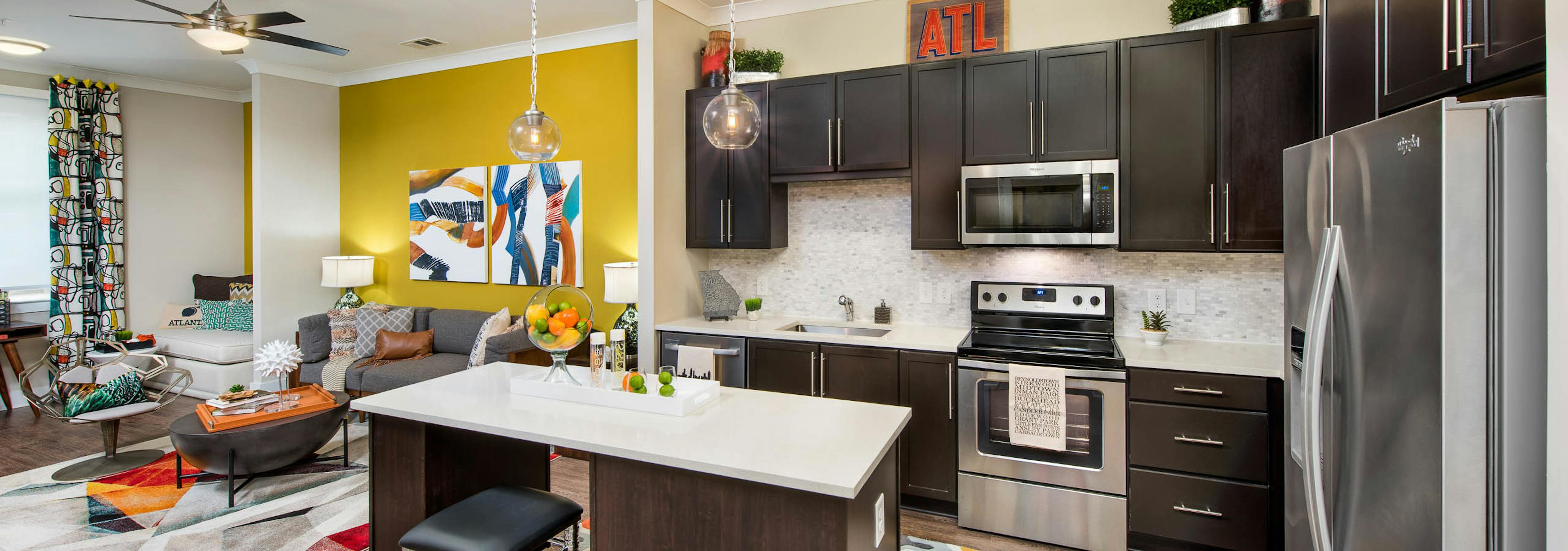 AMLI Buckhead kitchen with dark wood cabinets and quartz countertops and an island with living space visible in background