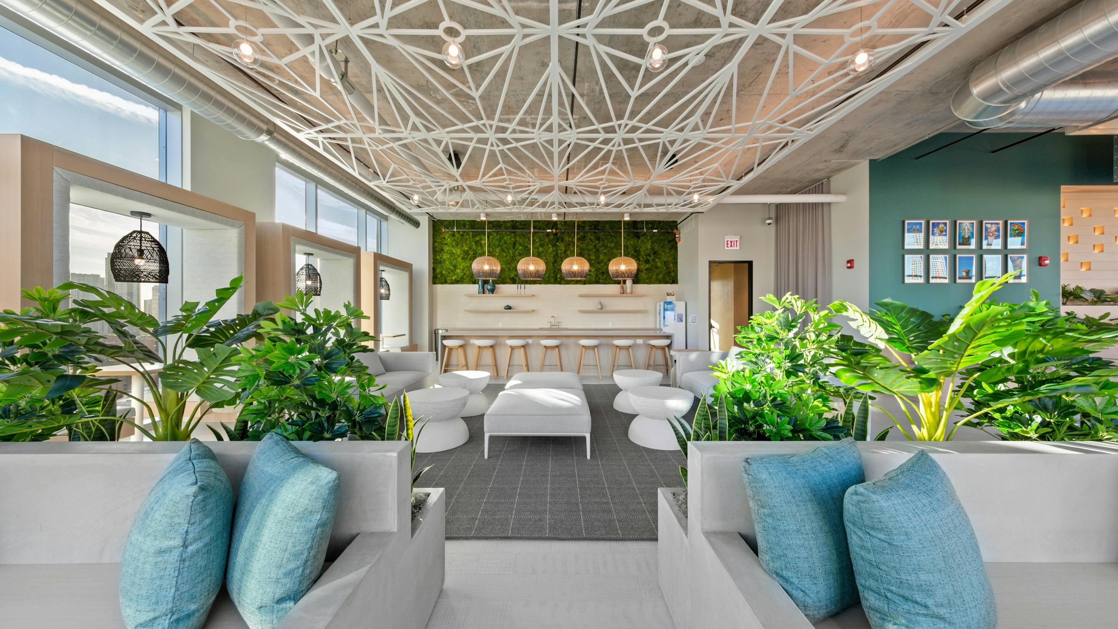 AMLI 808 resident lounge featuring white seating and accent tables with bar seating in background and modern ceiling decor