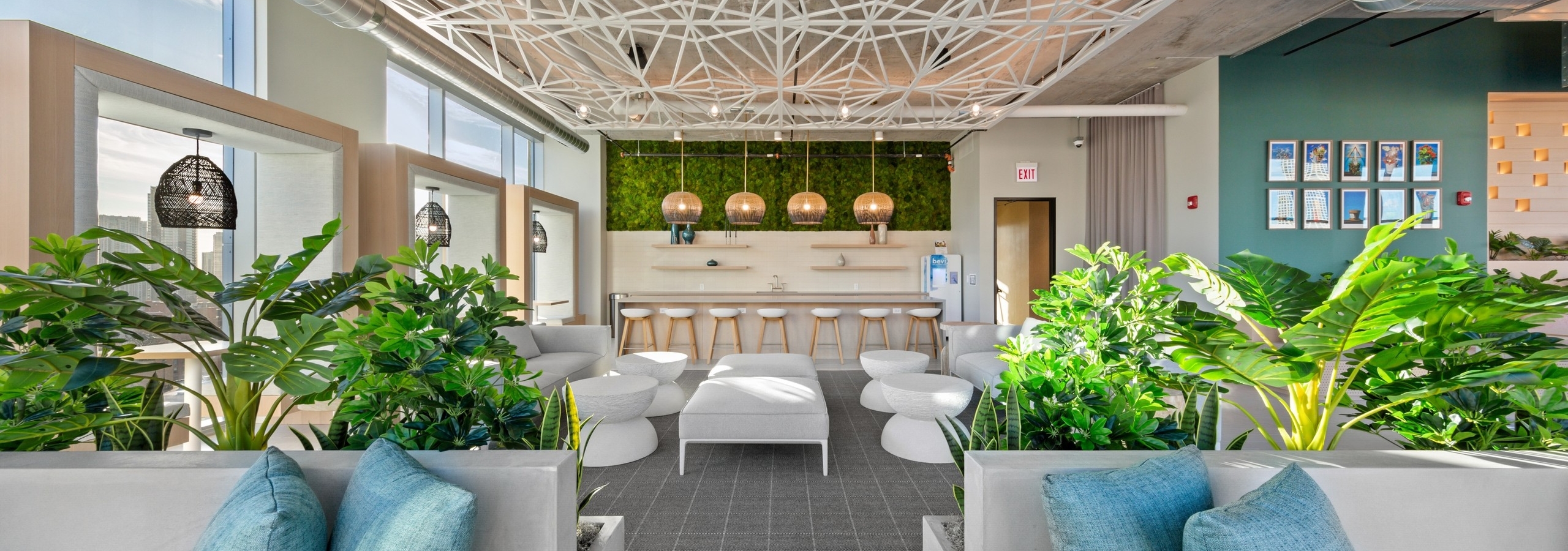 AMLI 808 resident lounge featuring white seating and accent tables with bar seating in background and modern ceiling decor