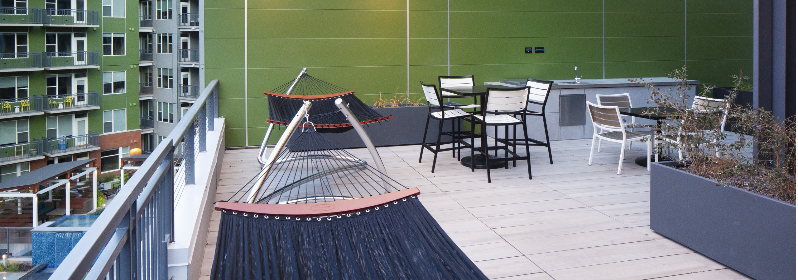 An evening view on the rooftop deck at AMLI Riverfront Green apartments with multiple hammocks with tables and chairs