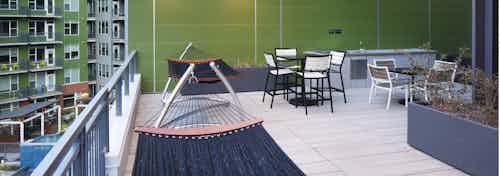 An evening view on the rooftop deck at AMLI Riverfront Green apartments with multiple hammocks with tables and chairs