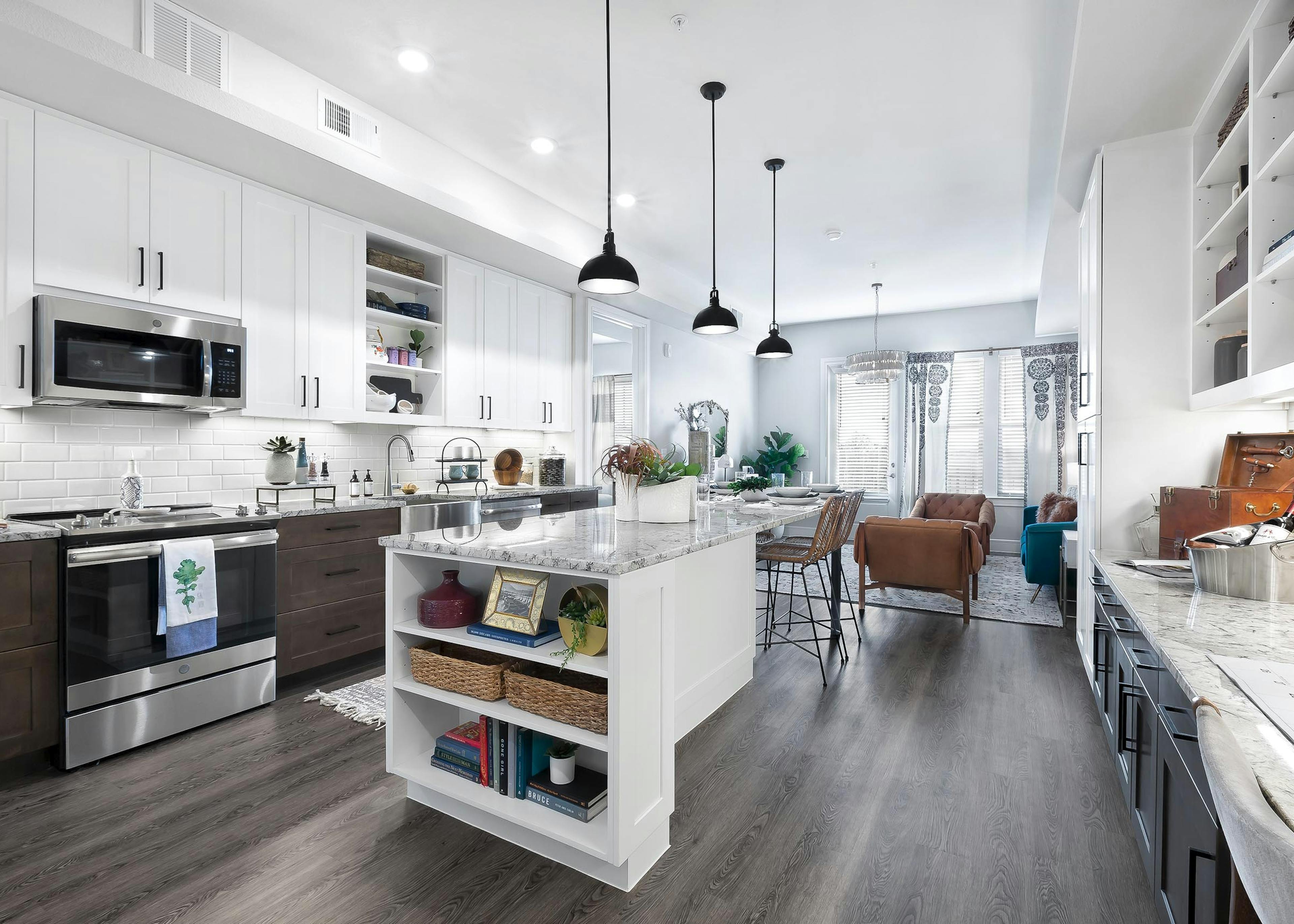 Interior view of kitchen at AMLI Lakeline with white and brown cabinets and a dining island with granite countertops