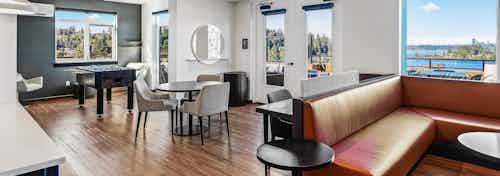 AMLI Bellevue Park sky lounge with brown leather couch and table and chairs and large windows with view of Lake Washington