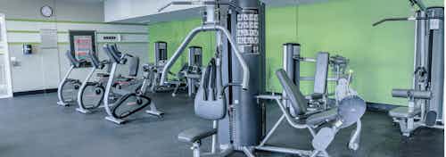 Interior view of a fitness center AMLI Arista apartments with strength training machines stationary bicycles and green walls