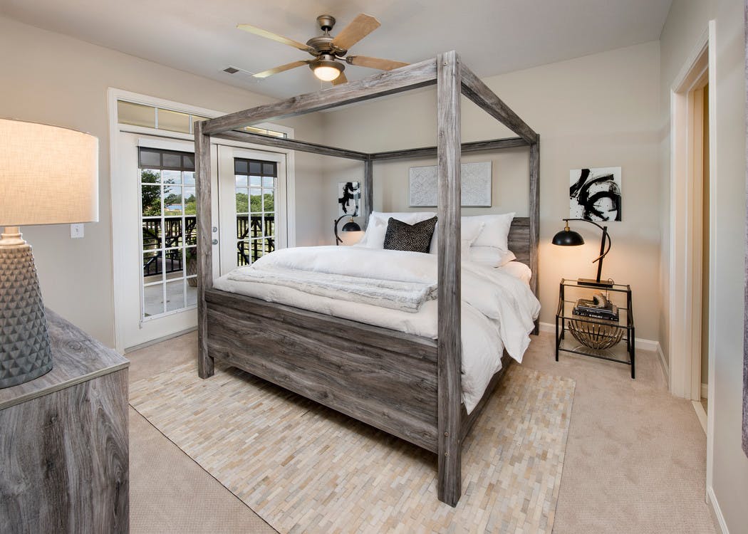 Bedroom at AMLI North Point with french doors leading outside and rustic styled decor with a canopy framed bed