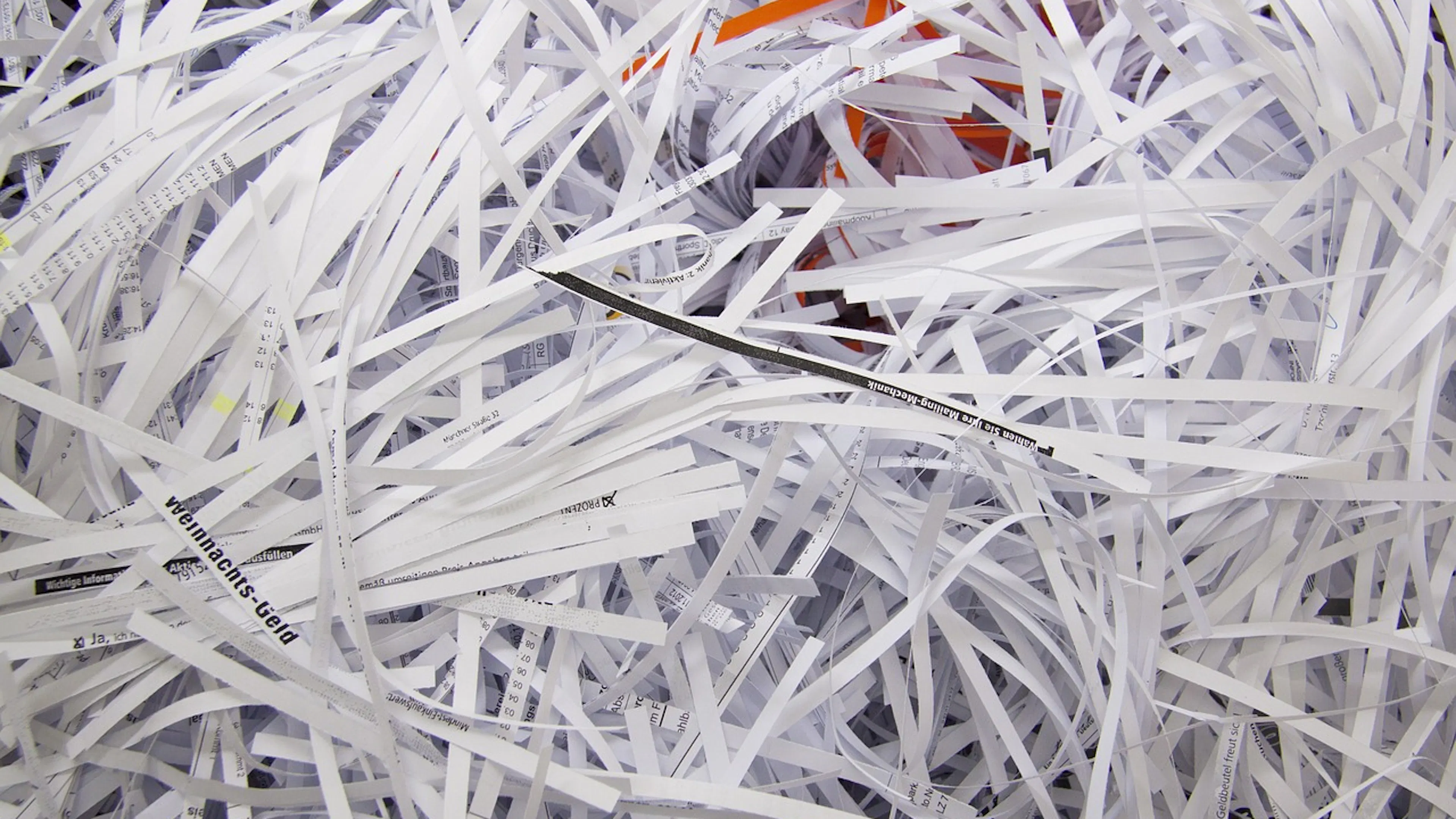 A close up of a big pile of shredded white office paper with colorful strips of shredded paper mixed in