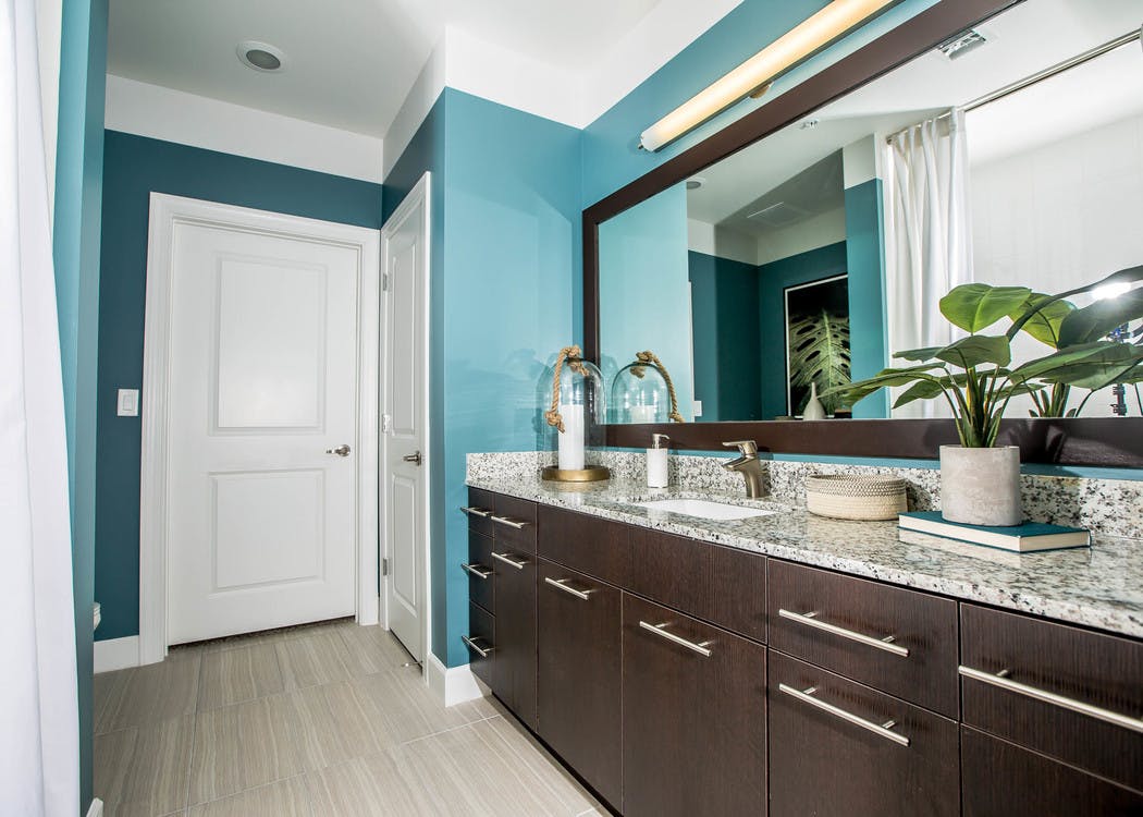 Interior view of a bathroom at AMLI Joya apartment with double sink vanity, large mirror on wall and granite counters