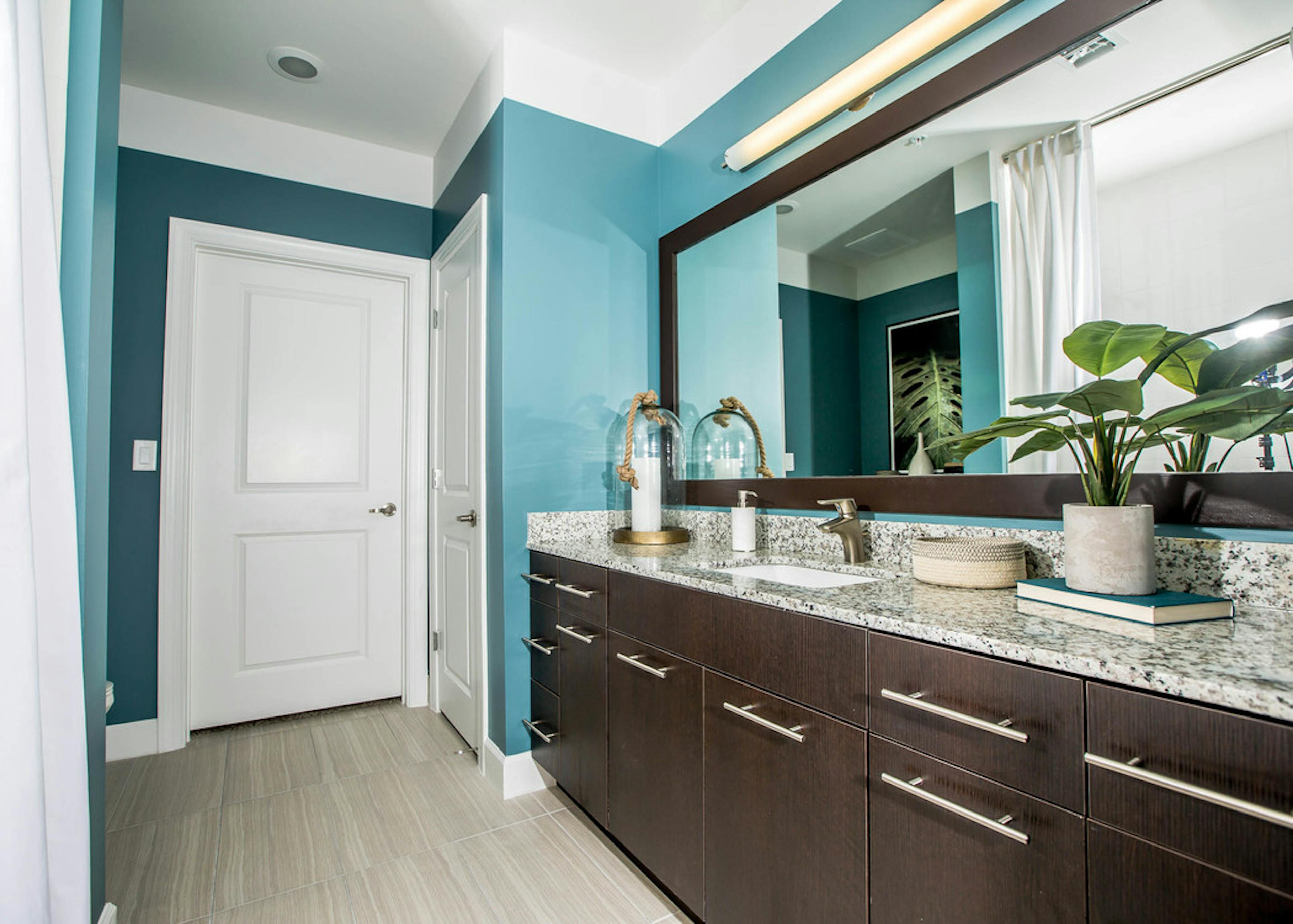 Interior view of a bathroom at AMLI Joya apartment with double sink vanity, large mirror on wall and granite counters