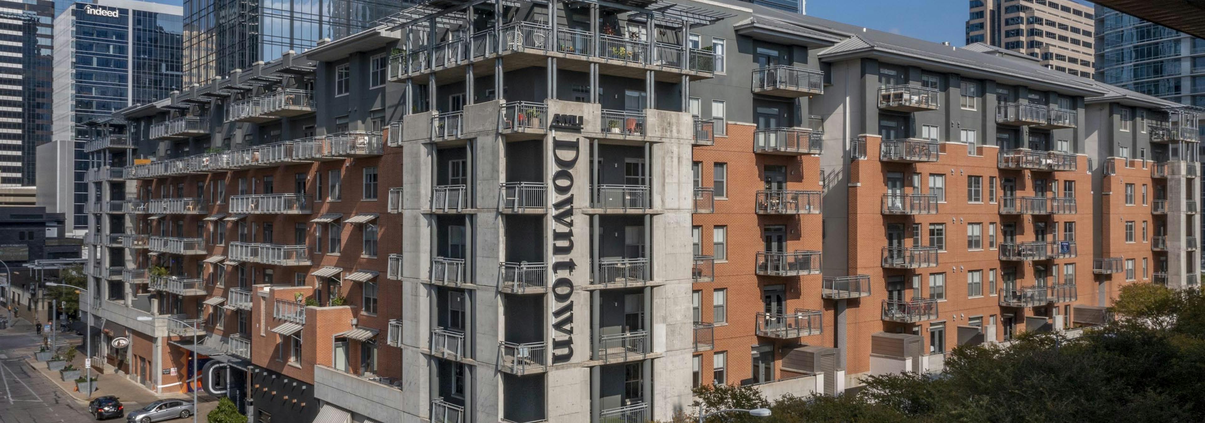 Daytime aerial view of AMLI Downtown apartment building orange brick exterior with city skyscrapers in the background