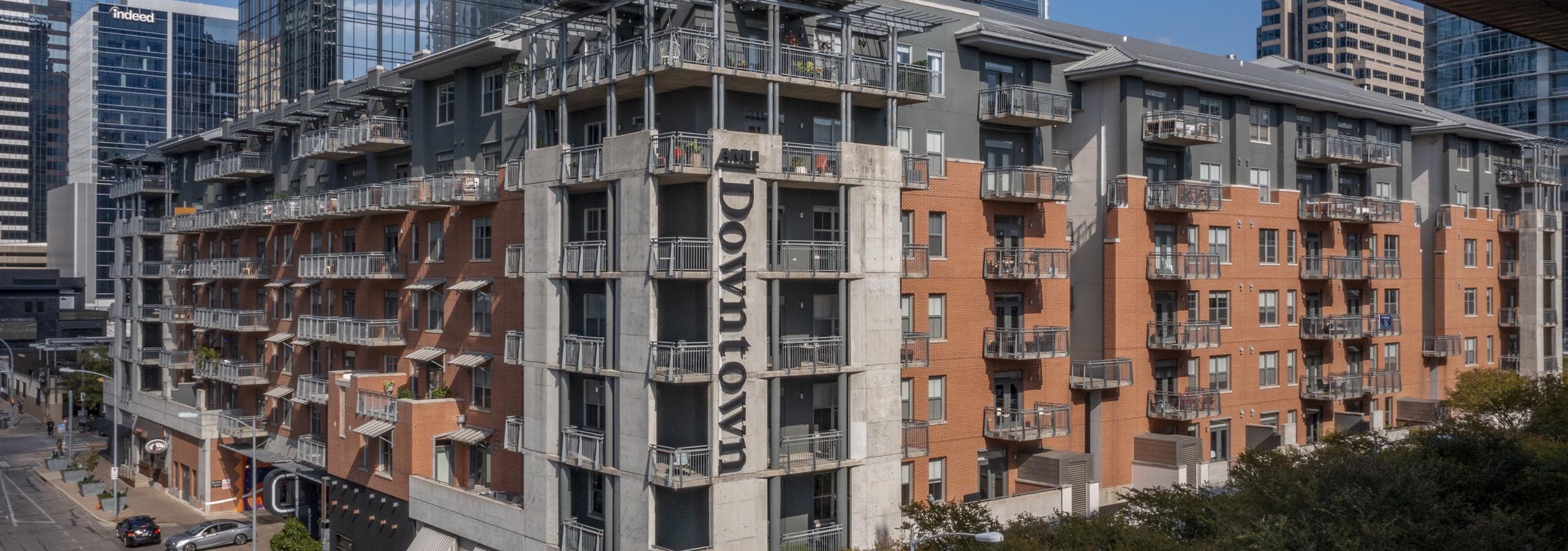 Daytime aerial view of AMLI Downtown apartment building orange brick exterior with city skyscrapers in the background