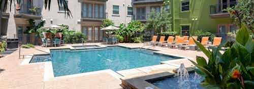 Exterior view of daytime AMLI 300 resort-style swimming pool with gas grills, lush greenery, and poolside dining