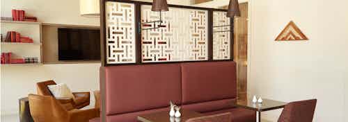 AMLI on Riverside resident lounge showing burgundy booth seating at two small tables with couch seating and flat screen TV