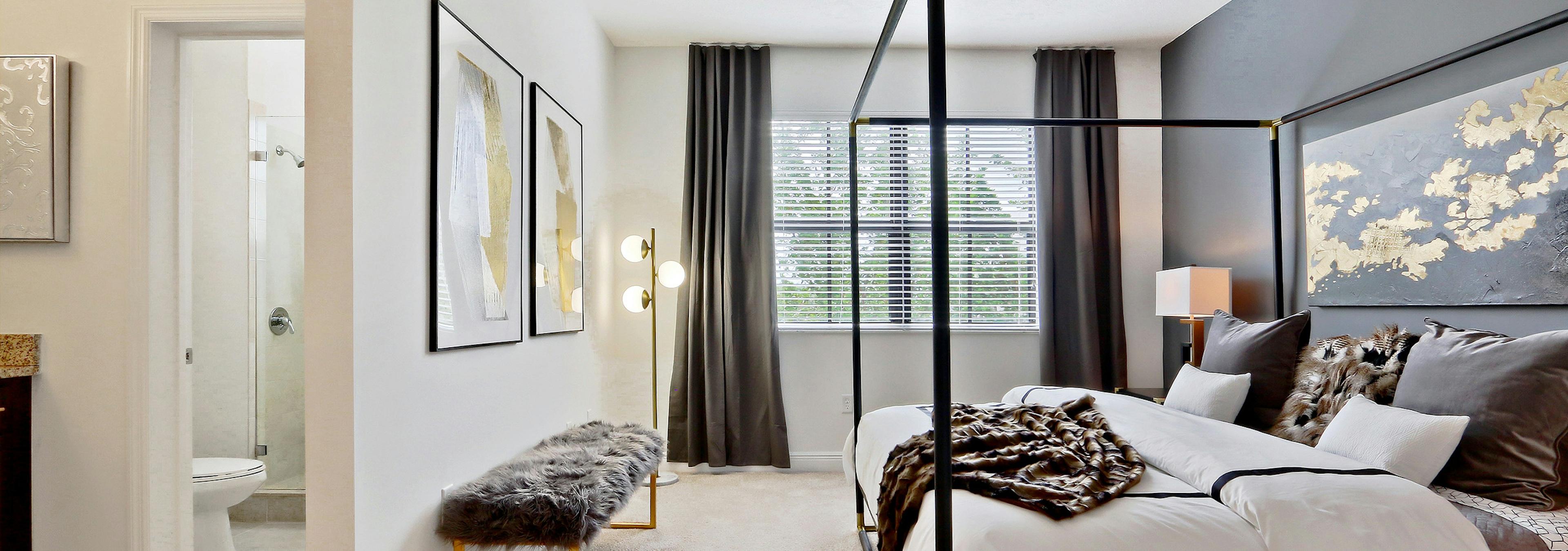 Interior view of AMLI Toscana Place townhome bedroom with bed centered on wall, view from a window and peek into bathroom