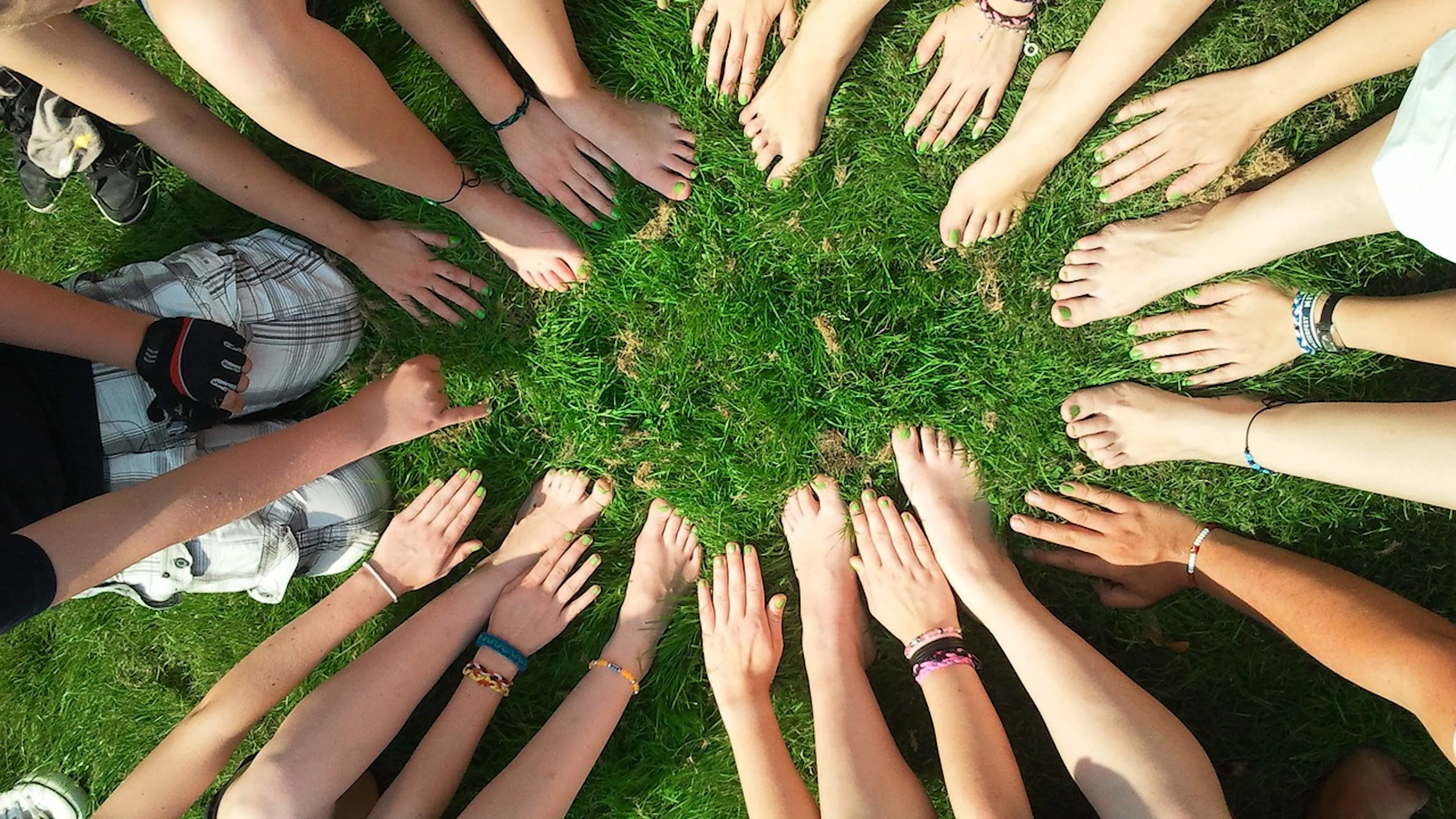 Cirlcle of hands and feet in green grass