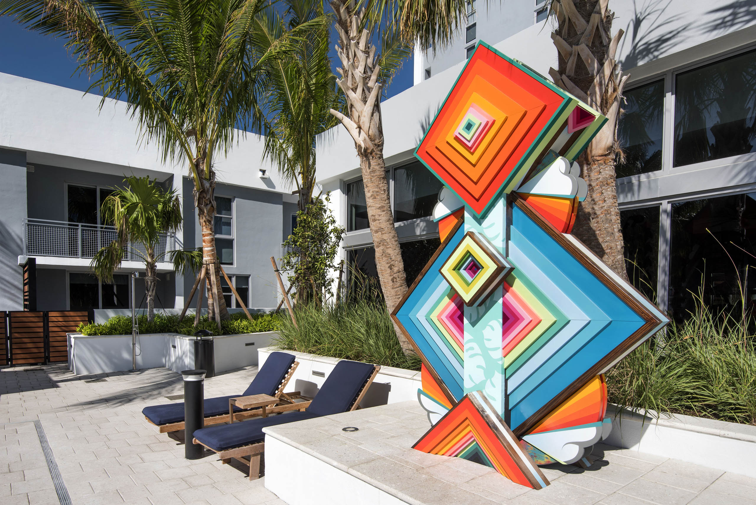 AMLI Midtown 29 apartments multi color layered geometric pool sculpture with navy lounge chairs and palm trees