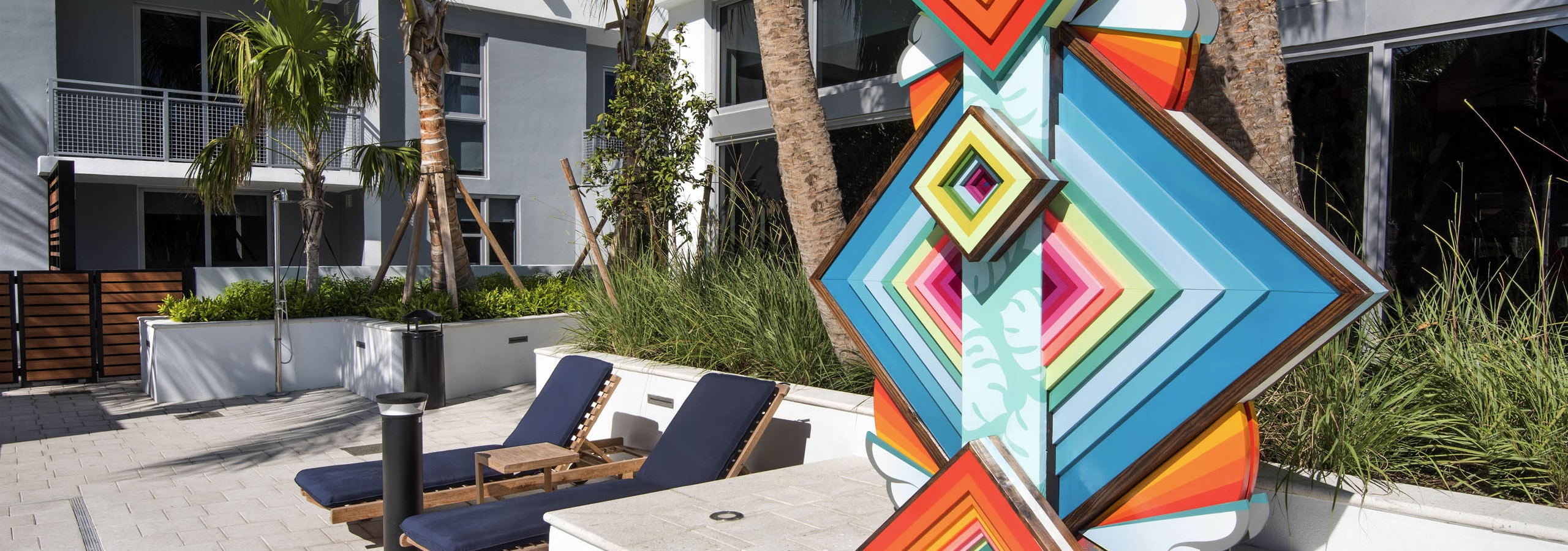 AMLI Midtown 29 apartments multi color layered geometric pool sculpture with navy lounge chairs and palm trees