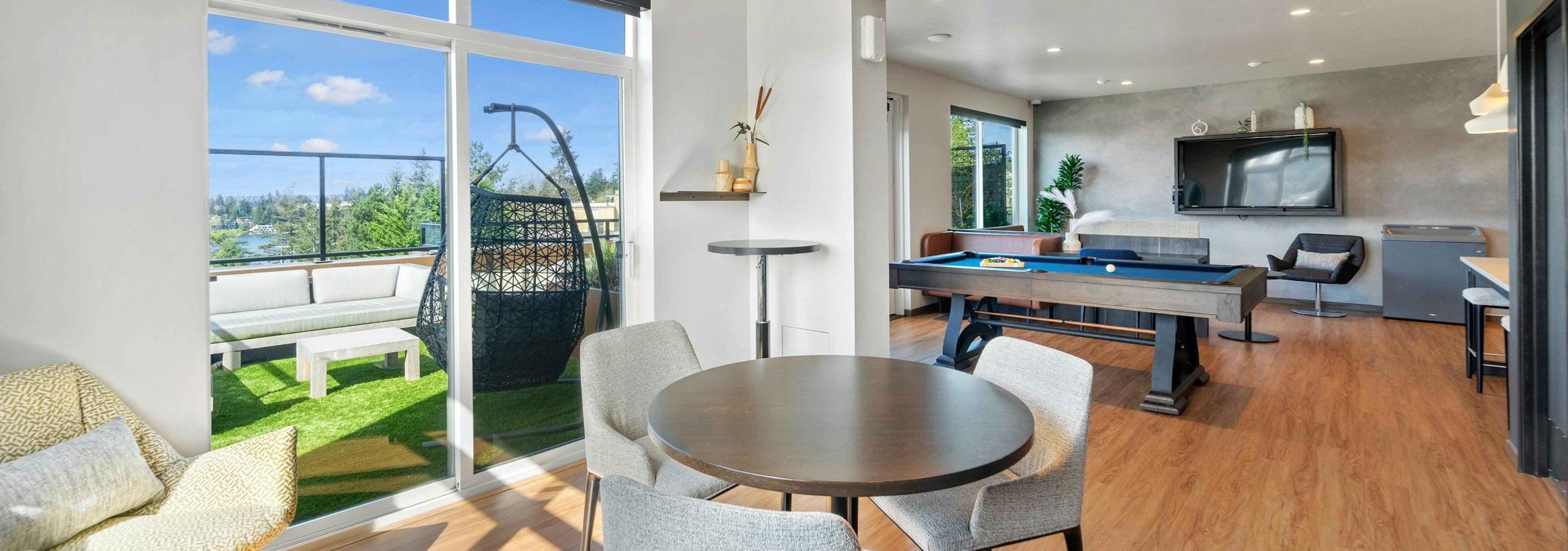 Interior view of AMLI Bellevue Park sky lounge with table and chairs and billiards and TV with view to outside lounge 