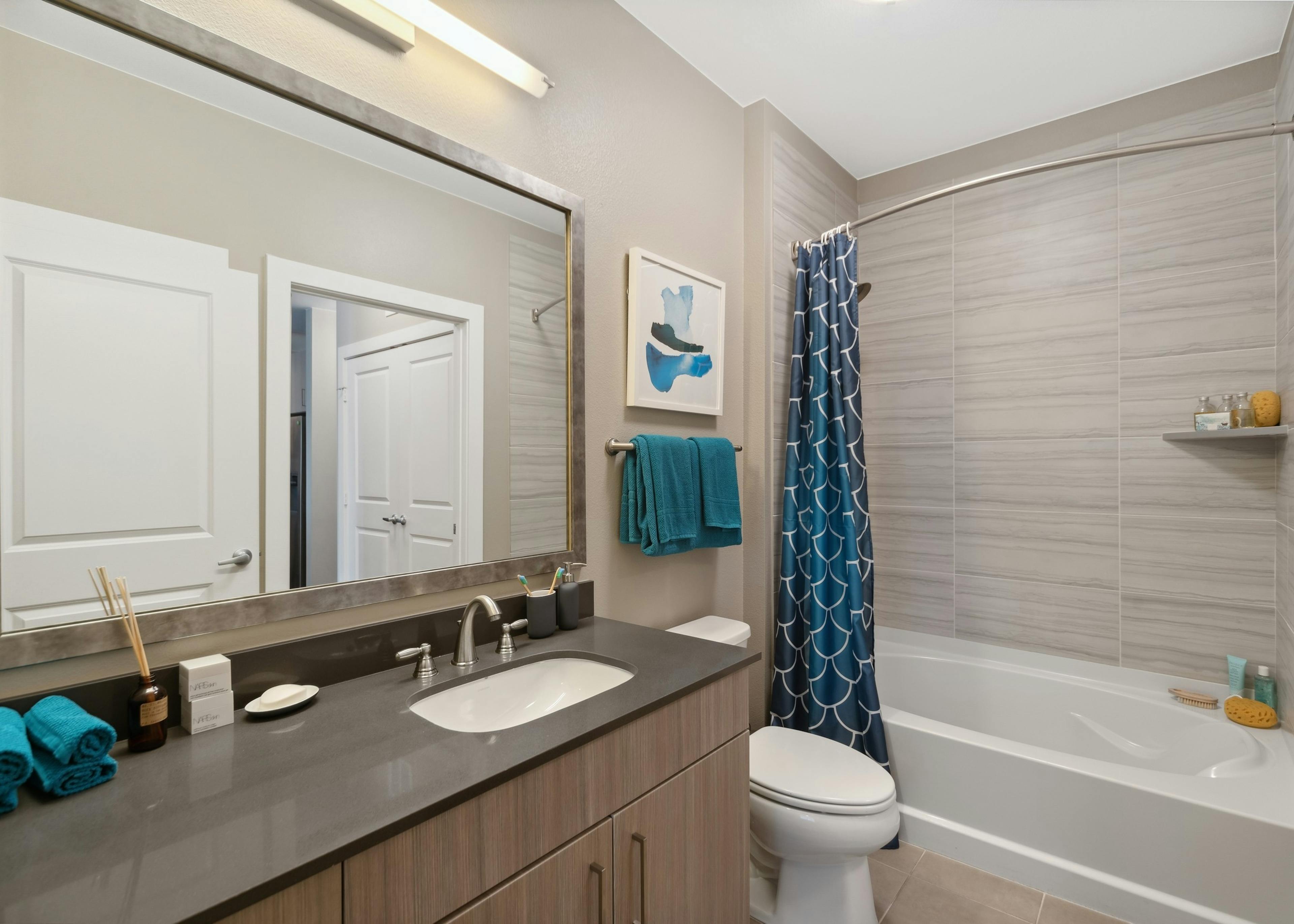 Interior of a bathroom at AMLI Dry Creek apartments with black counter and brown vanity and white soaking tub