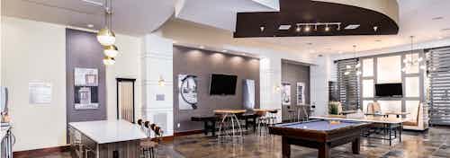 Interior view of the club room at AMLI Park Avenue apartments with a pool table and multiple seating areas and wall art work