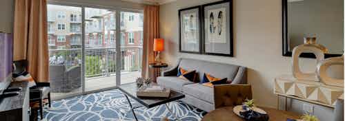 AMLI Deerfield living room with balcony overlooking courtyard view and furnished with couch and coffee table and décor