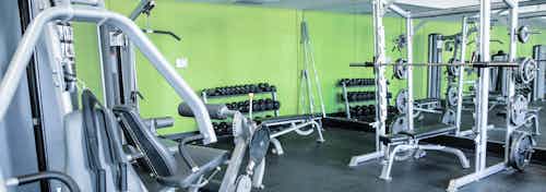 A fitness center at AMLI Arista apartments with an up close view of strength training machines and a bench press with mirrors
