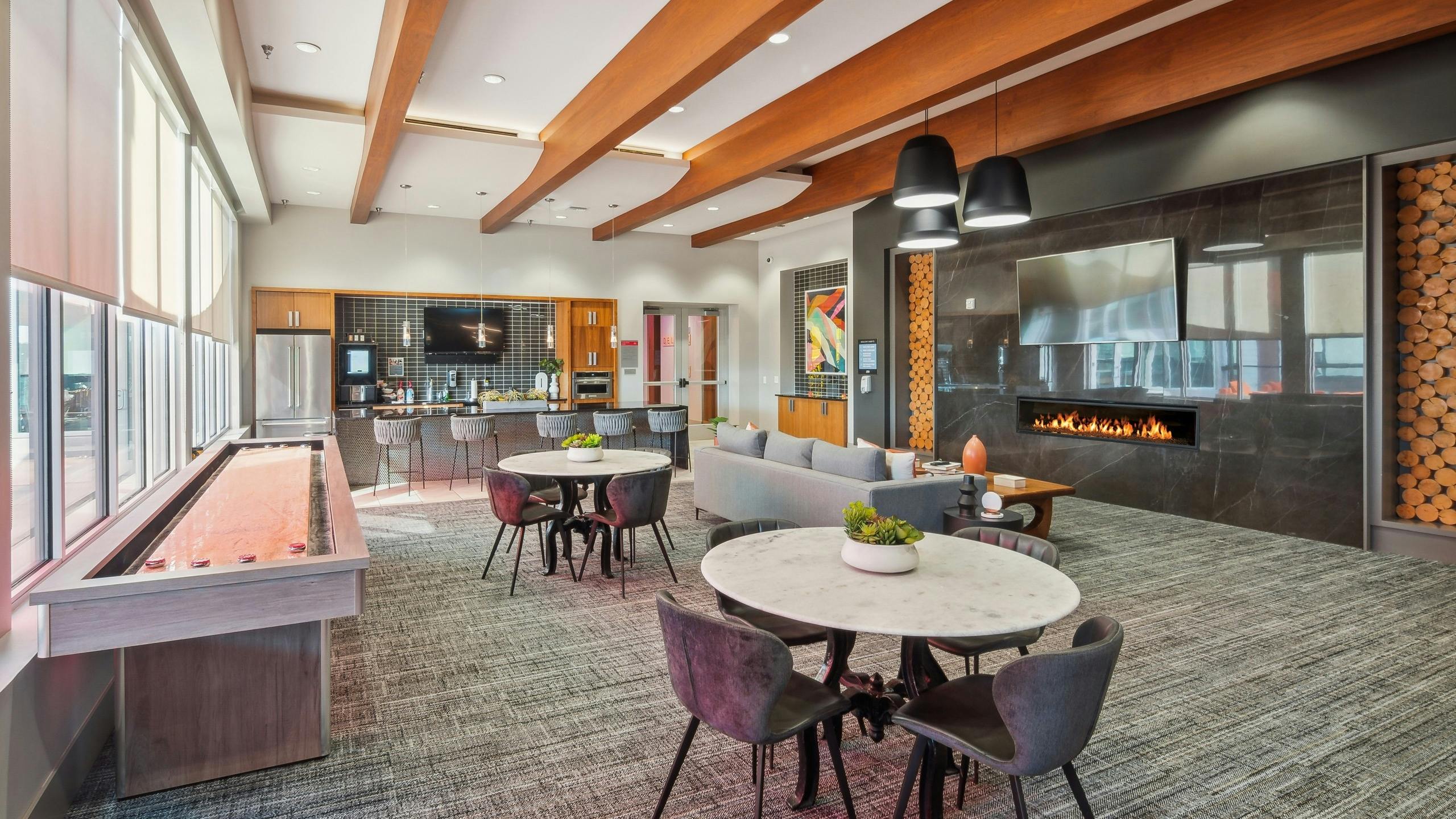 Clubroom at AMLI Denargo Market with wood rafters and game table and tables and chairs and couch across from fireplace and TV
