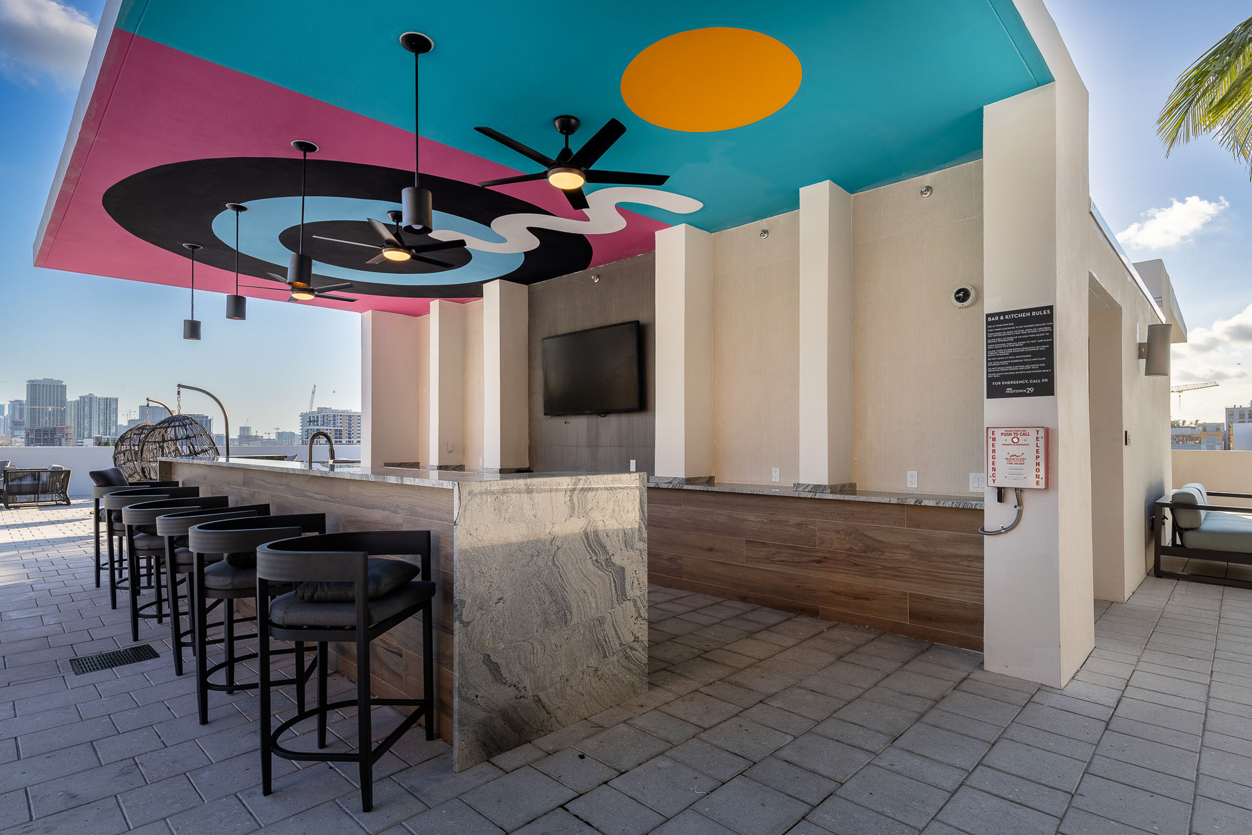 Rooftop pool bar with ceiling depicting colorful bullseye at AMLI Midtown 29 apartments with big screen TV and brown stools