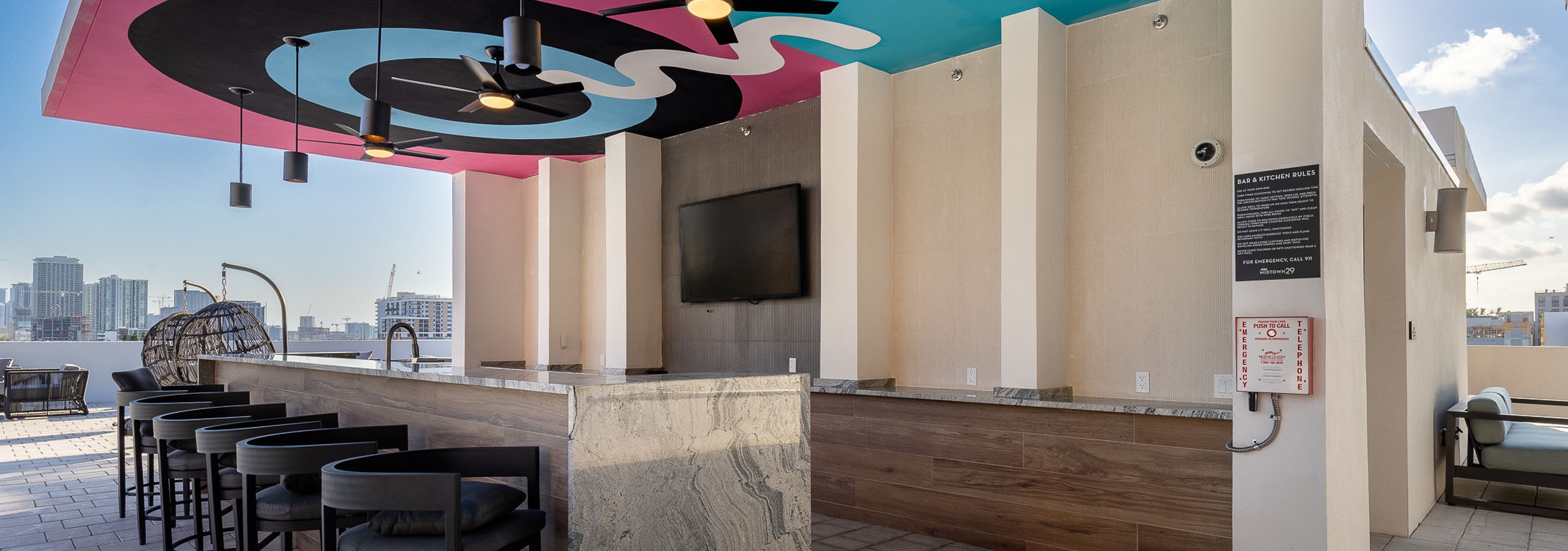 Rooftop pool bar with ceiling depicting colorful bullseye at AMLI Midtown 29 apartments with big screen TV and brown stools