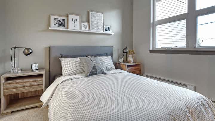 Interior view of AMLI Mark24 bedroom with view of walk-in closet sliding barn door light grey walls and two bedside tables