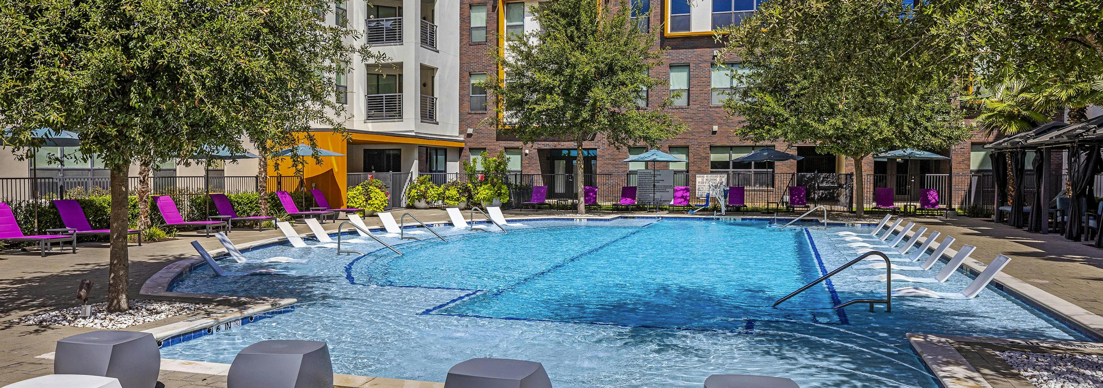 Daytime view of AMLI on Aldrich courtyard pool with shaded cabanas and pink lounge seating around perimeter