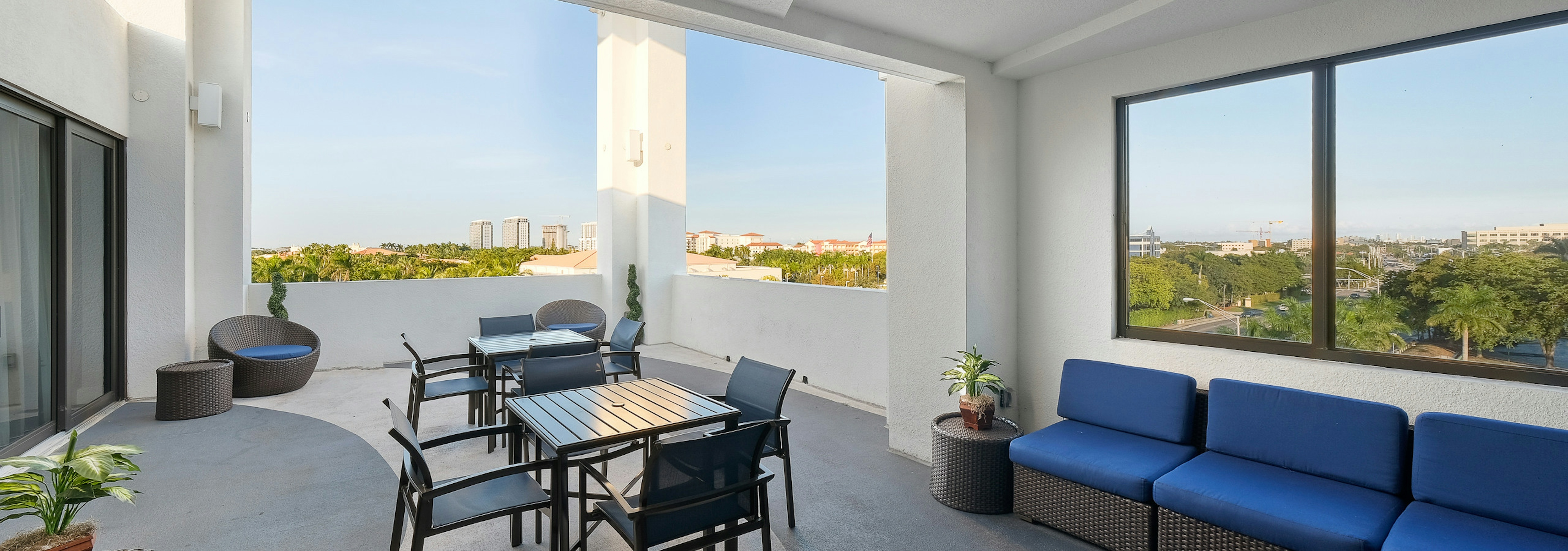 AMLI 8800 exterior skyline view of the rooftop terrace with table and chairs and blue sofa seating area