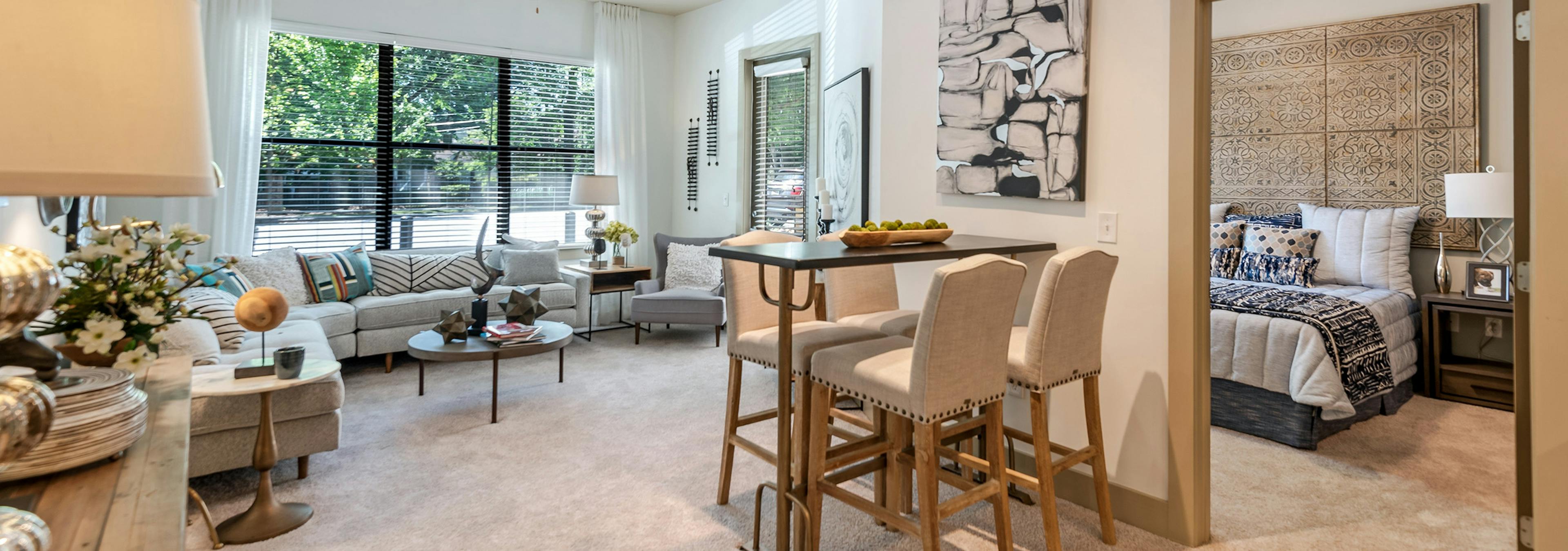 Interior of AMLI Parkside apartment living room with carpet and cream walls with a peek inside bedroom through open door