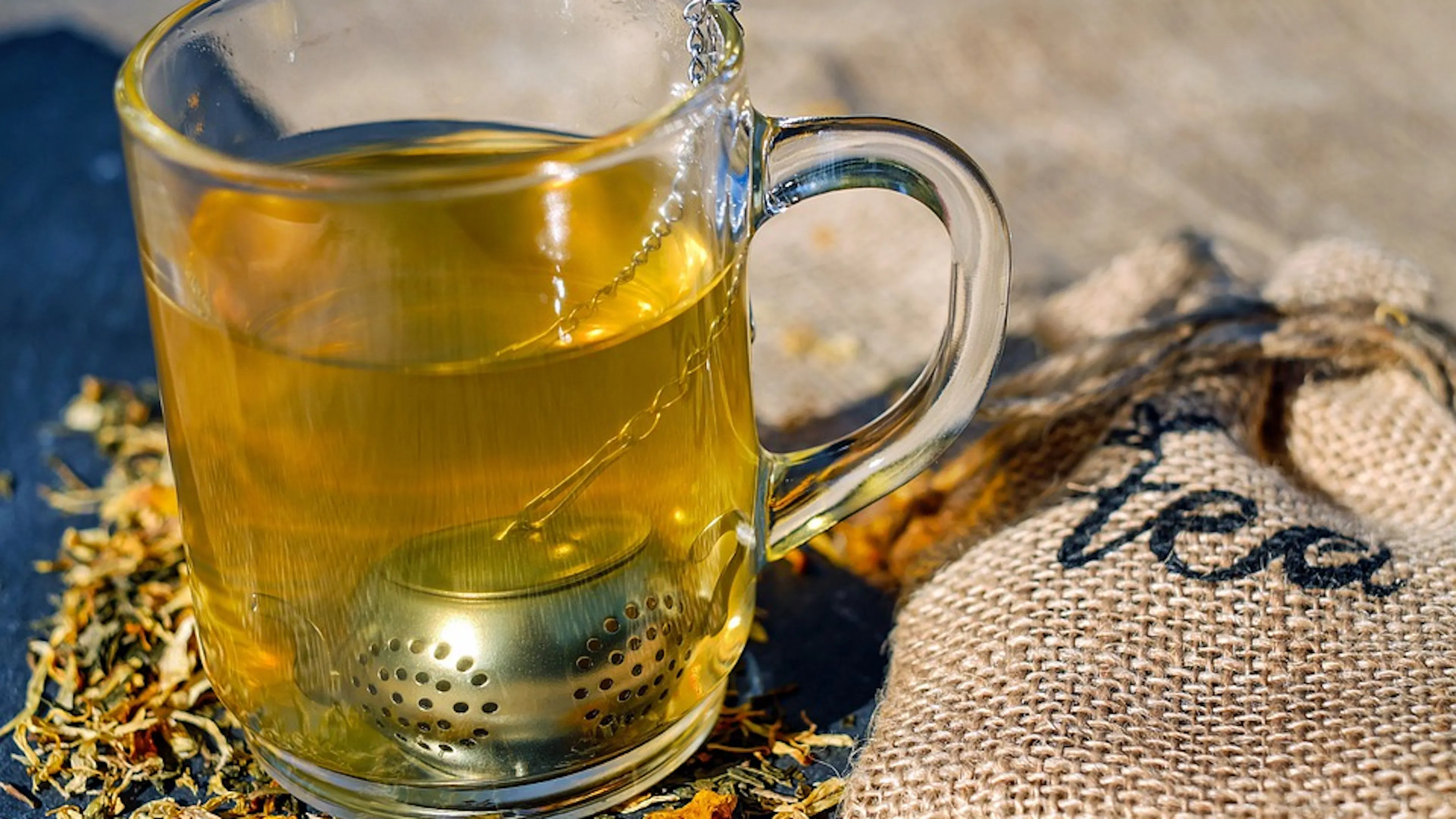 A glass mug with a tea strainer and a full mug of 
herbal tea