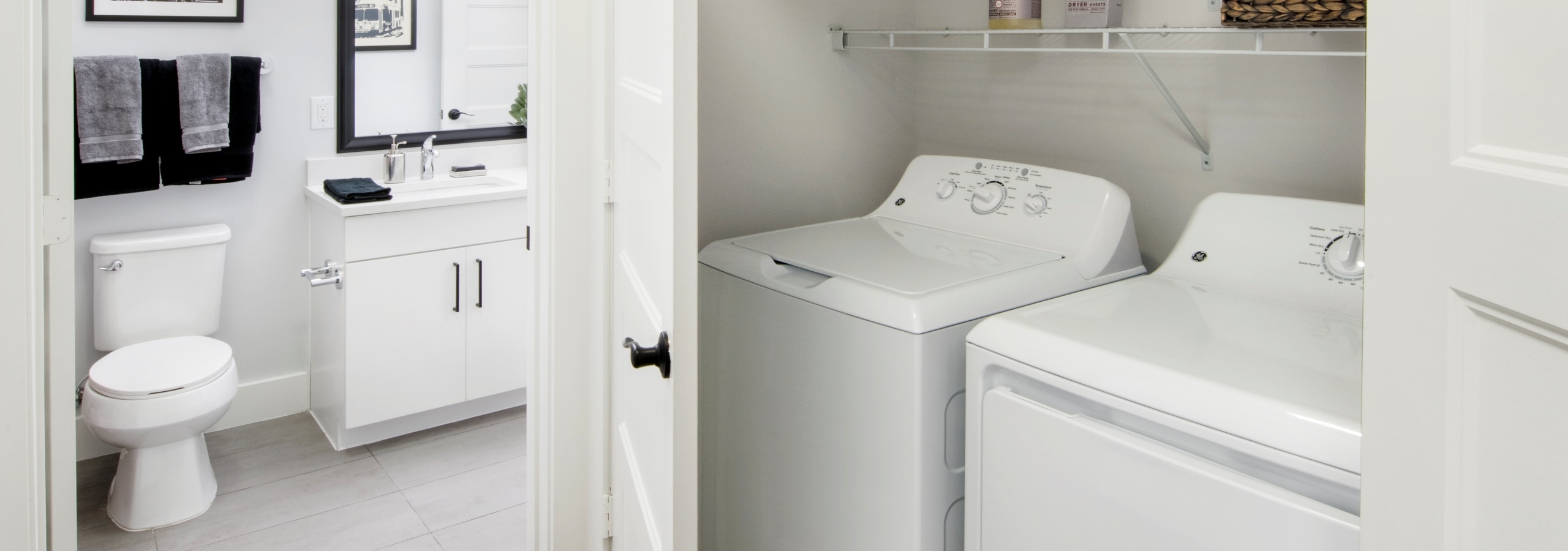 Interior of AMLI Decatur apartment with full size side by side washer and drier with shelves above and door open to bathroom