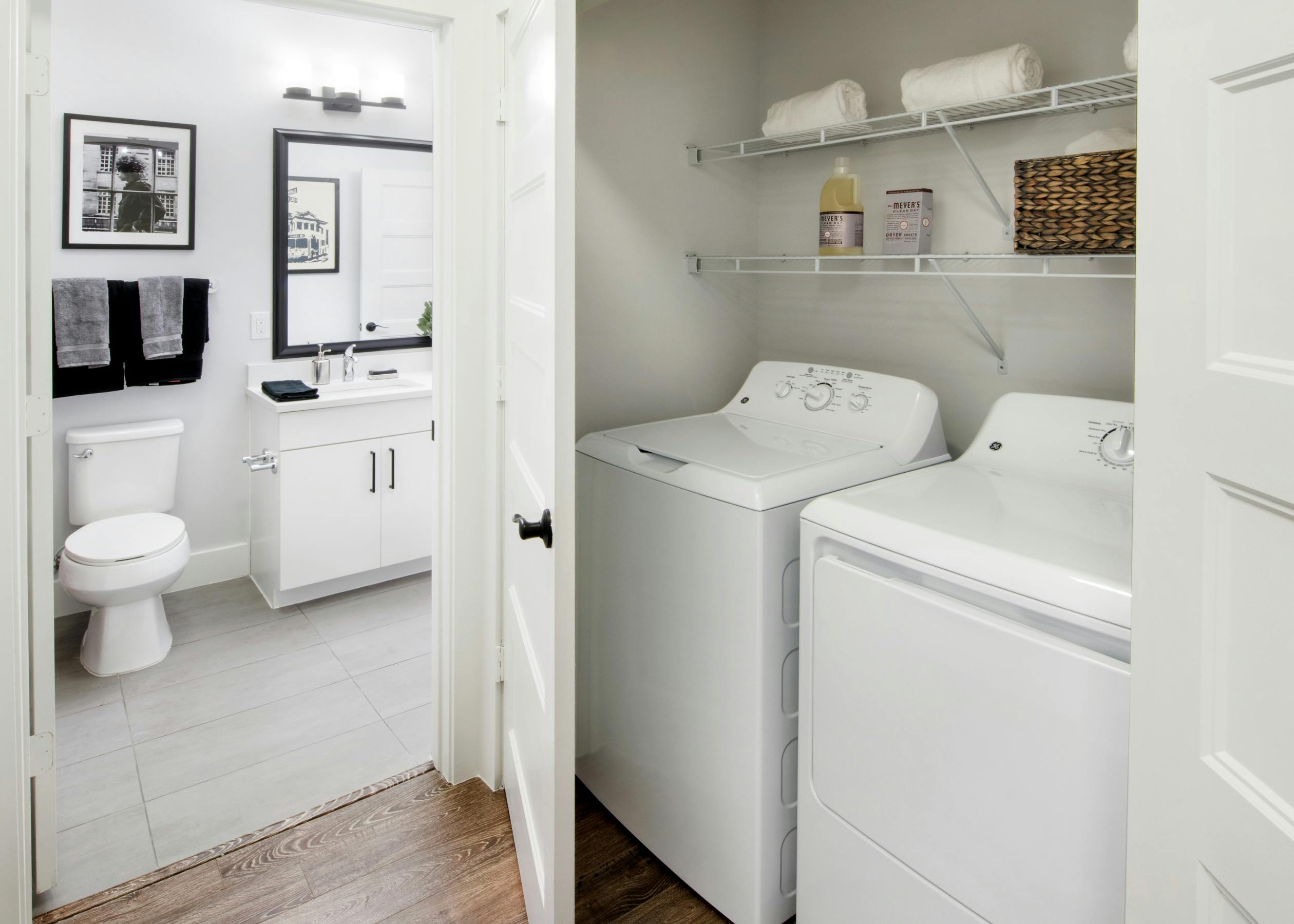 Interior of AMLI Decatur apartment with full-size side-by-side washer and drier with shelves above and door open to bathroom