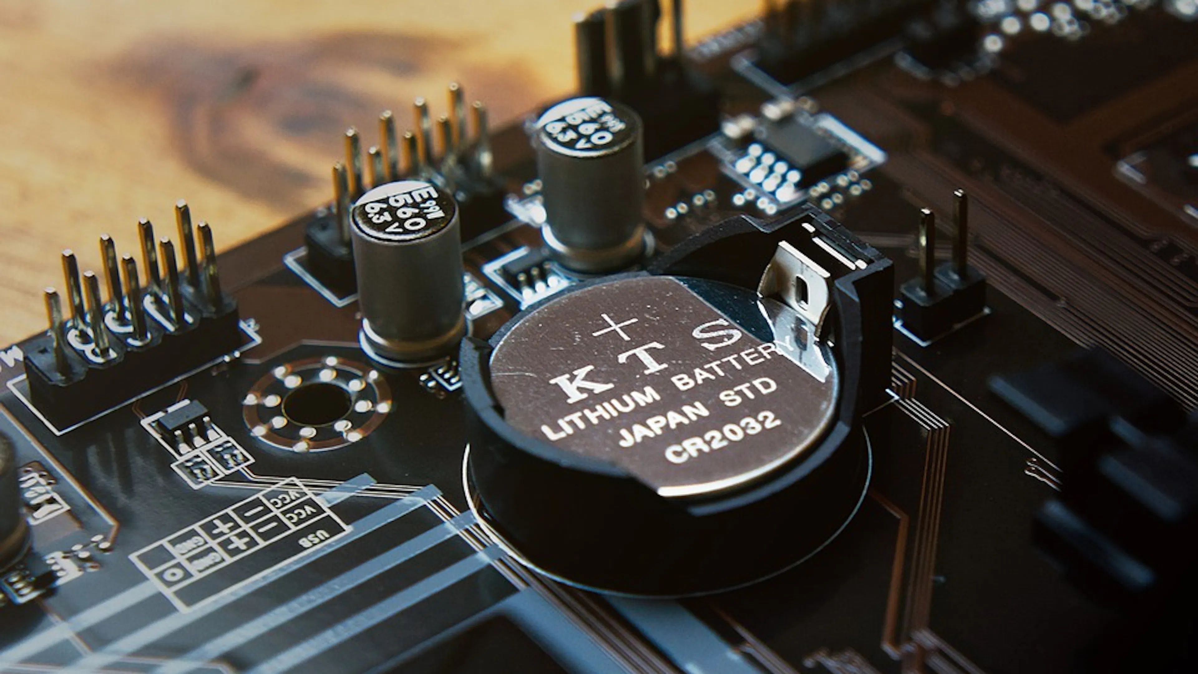 A close up of a round lithium battery in the middle of a circuit board 
