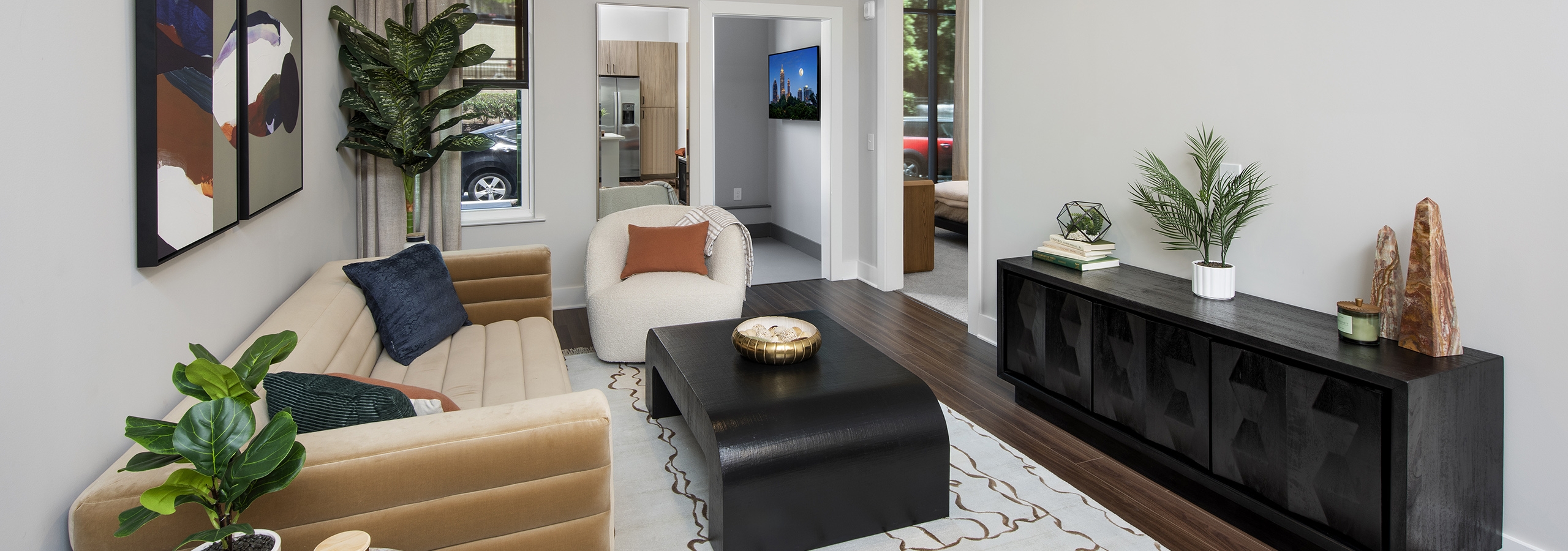 Living room at AMLI Flatiron apartments with light area rug under tan couch with white chair and dark wood accent tables
