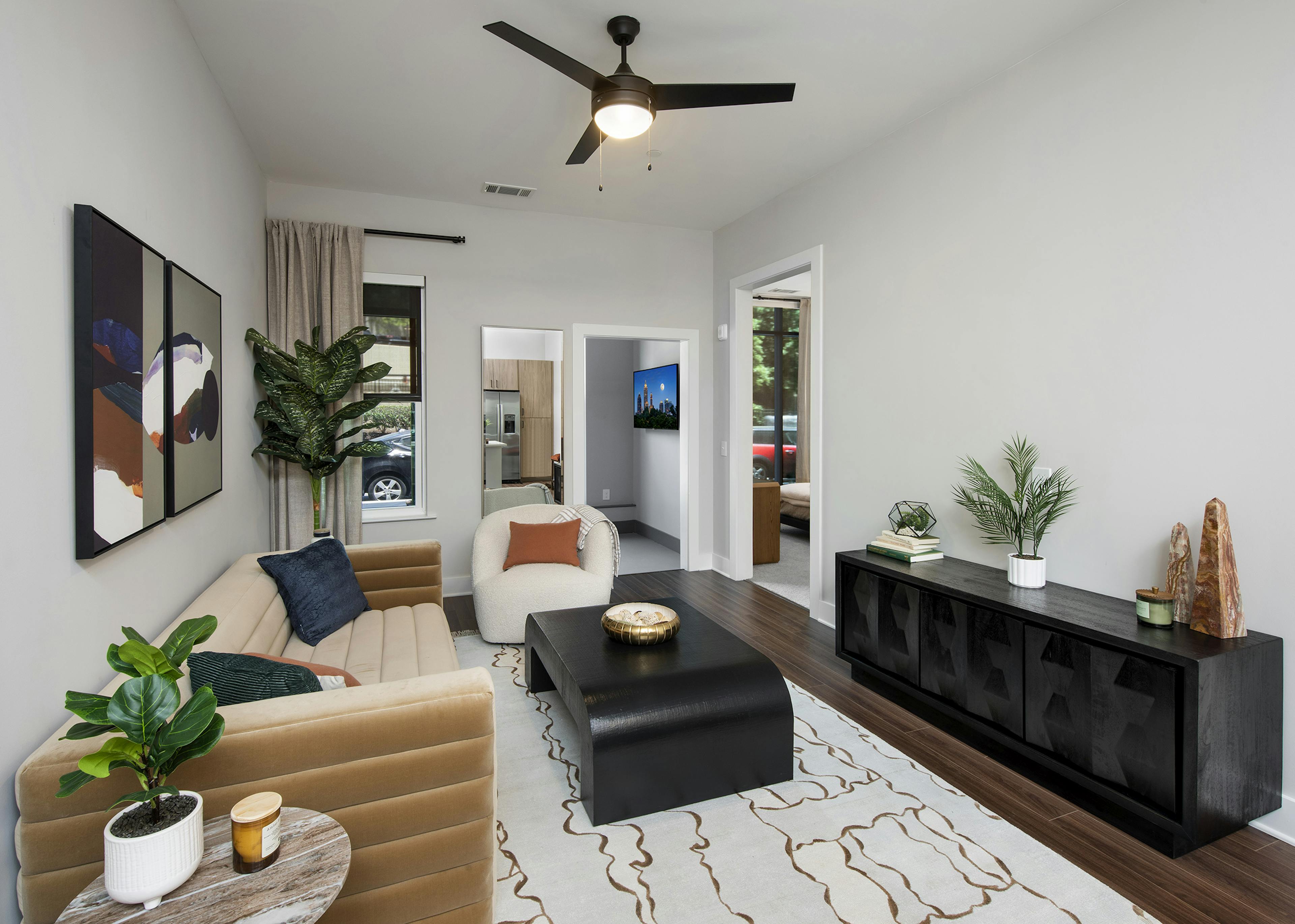 Living room at AMLI Flatiron apartments with light area rug under tan couch with white chair and dark wood accent tables