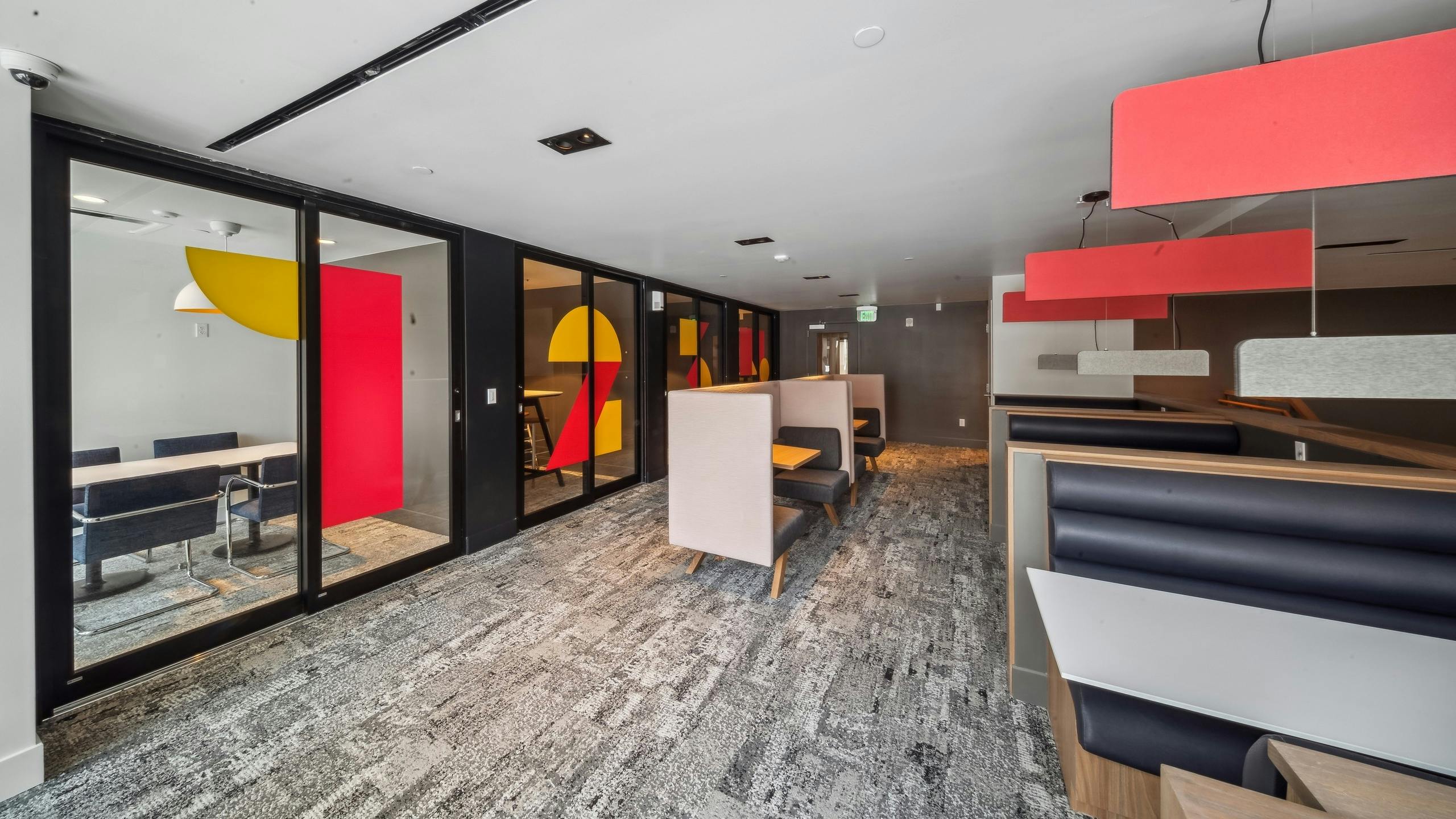 Co-working space at AMLI Broadway Park featuring private offices with sliding glass doors and additional tables and chairs