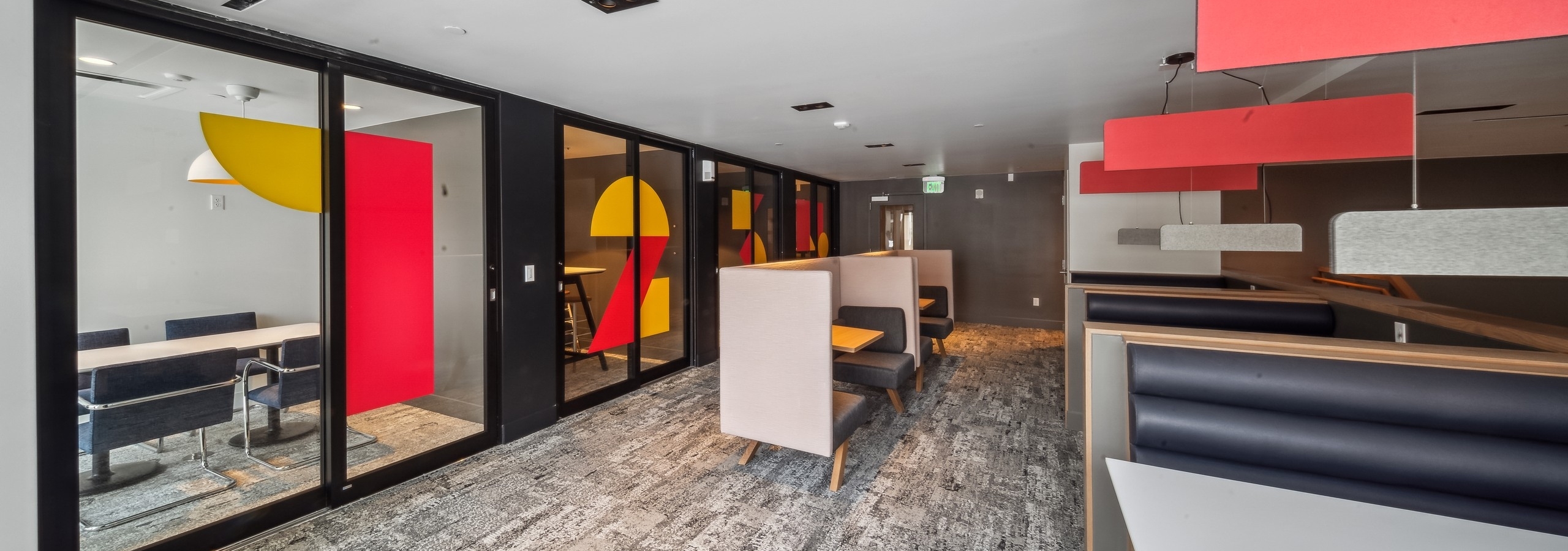 Co-working space at AMLI Broadway Park featuring private offices with sliding glass doors and additional tables and chairs