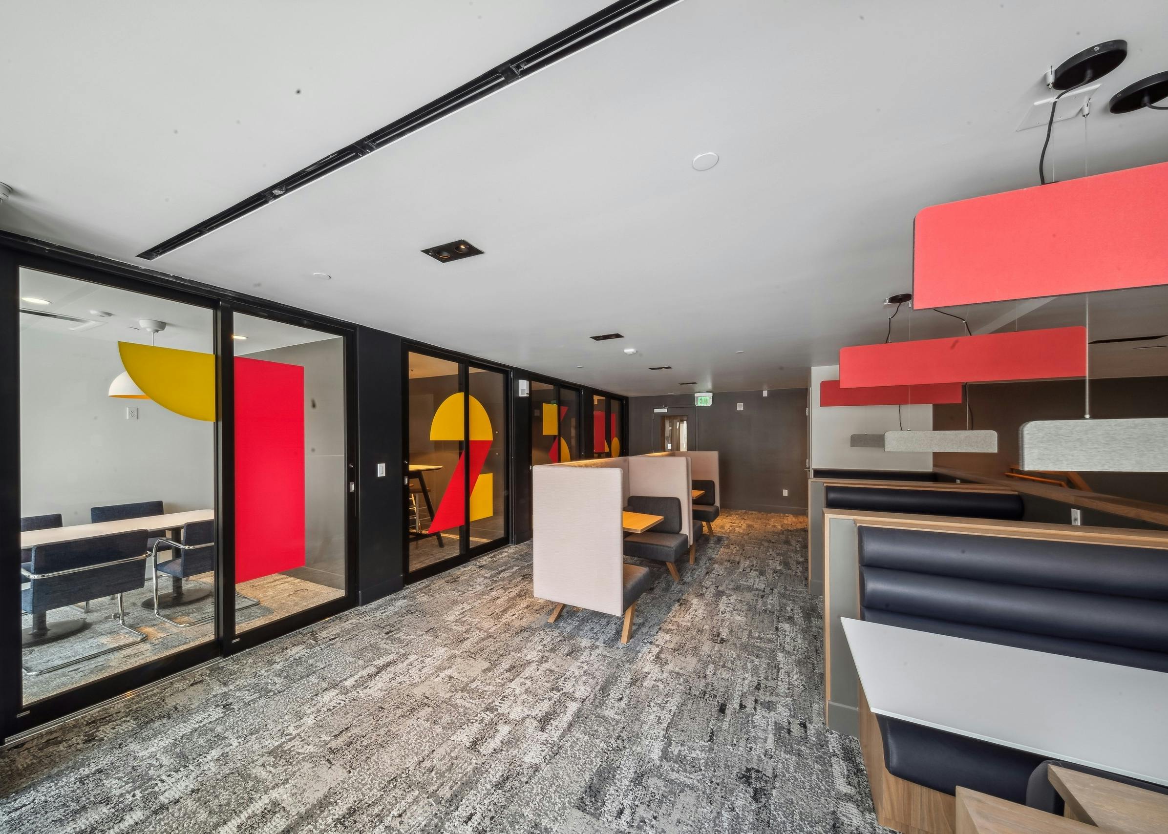 Co-working space at AMLI Broadway Park featuring private offices with sliding glass doors and additional tables and chairs