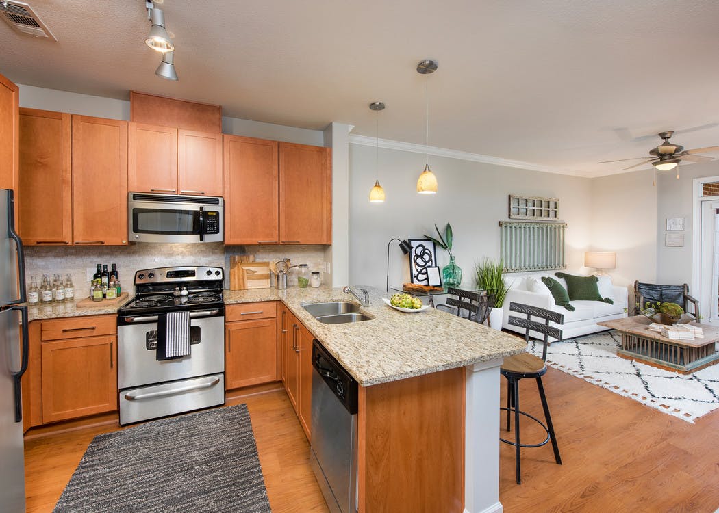 Interior of AMLI North Point kitchen with granite countertops and barstools at a counter which connects to living area