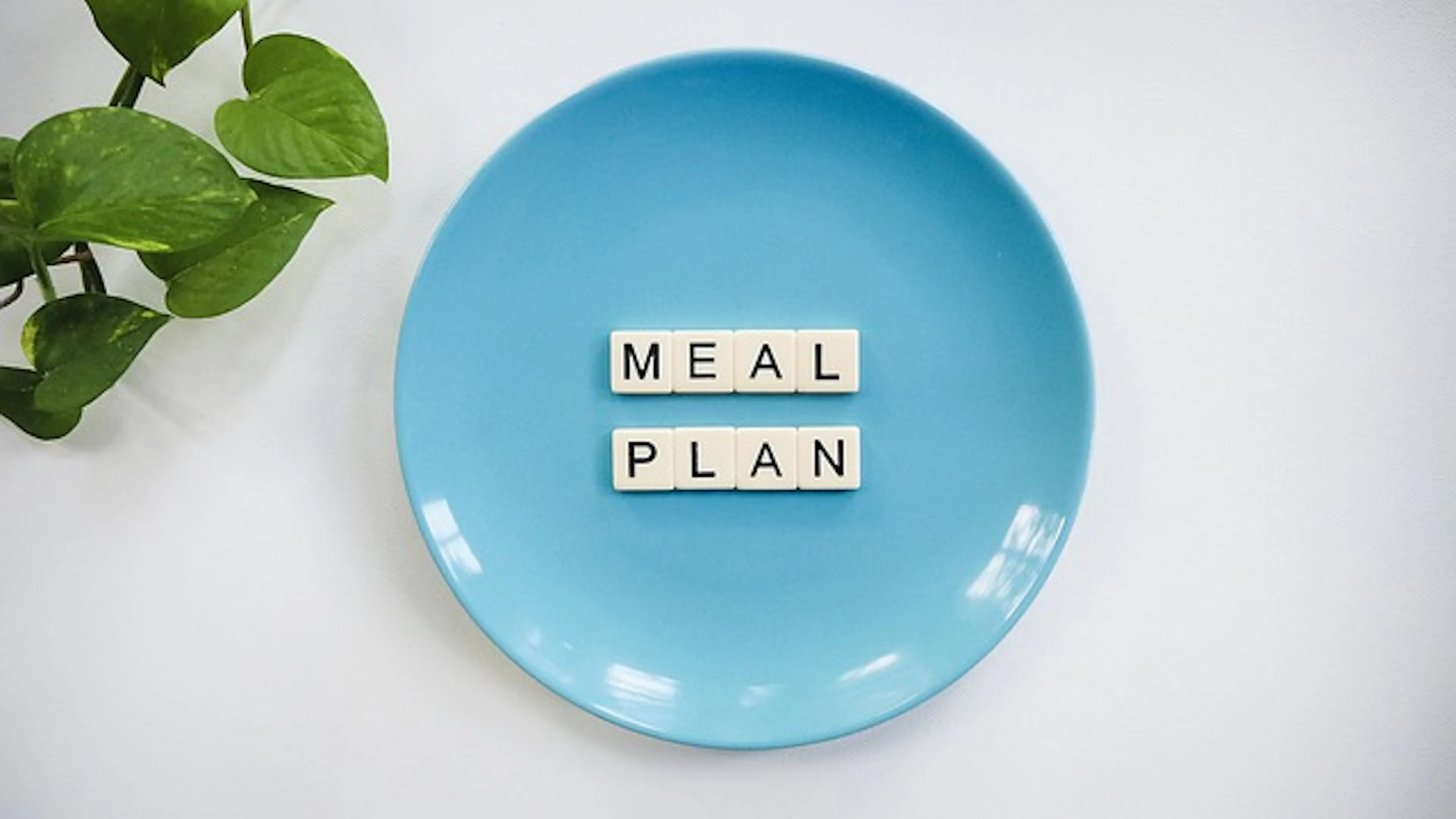A blue plate with Scrabble letters spelling out meal plan on top of the plate