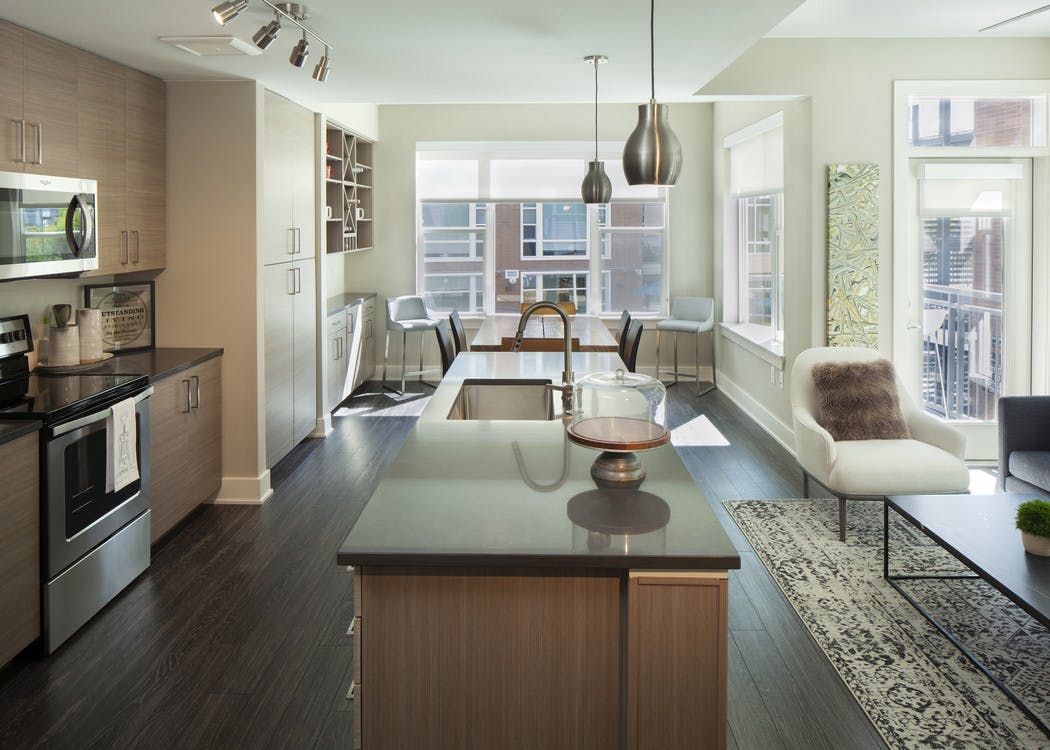 Interior view of AMLI Riverfront Green apartment kitchen and living room with dining room table and view of patio door