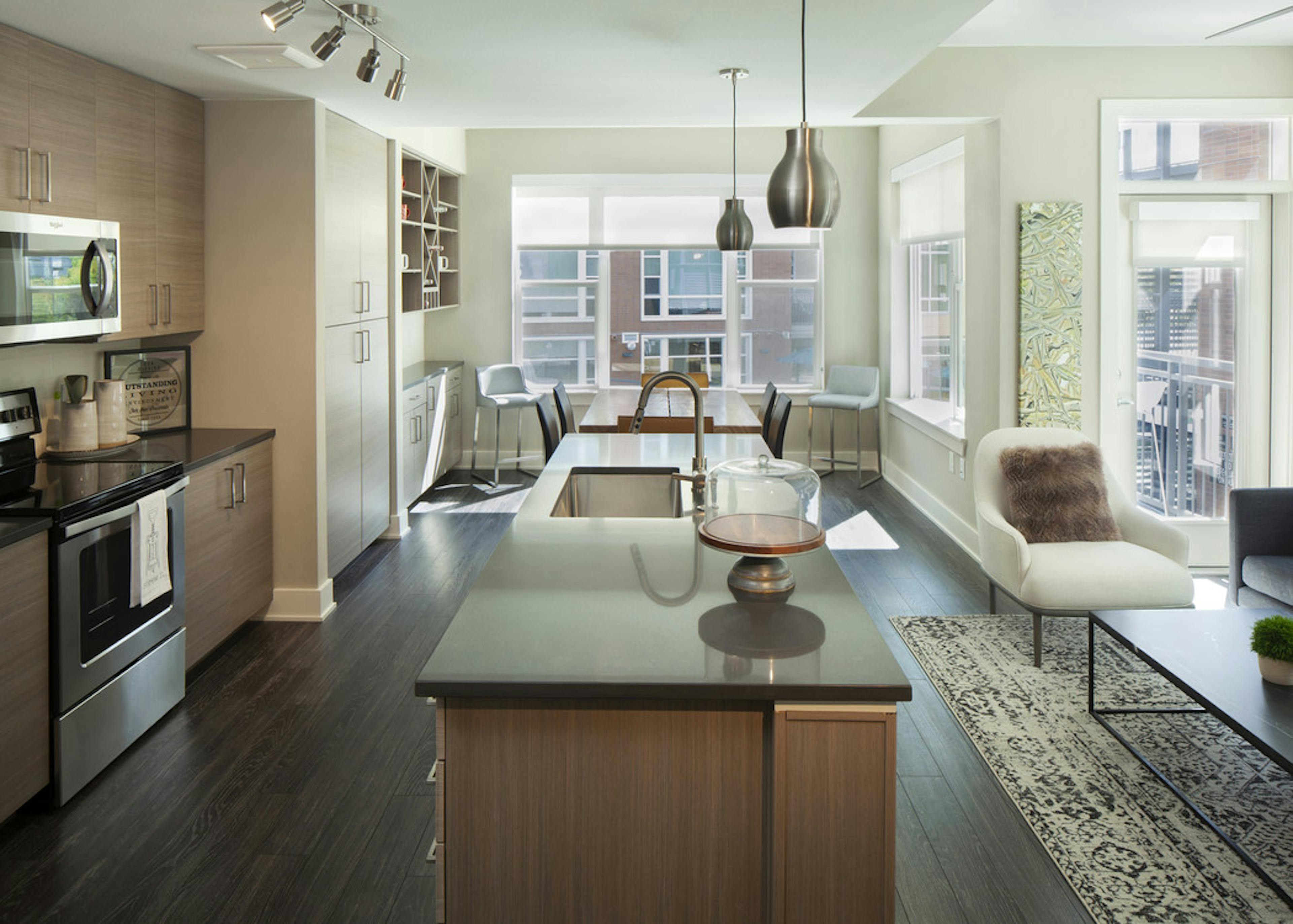 Interior view of AMLI Riverfront Green apartment kitchen and living room with dining room table and view of patio door
